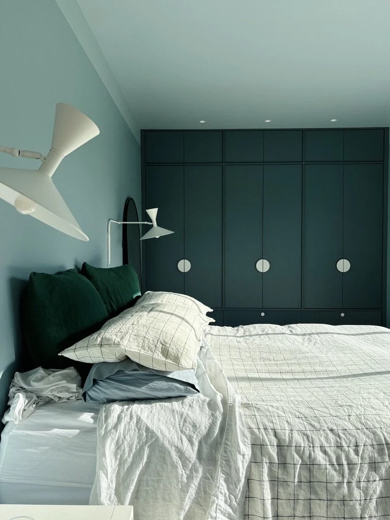 Deep teal built-in wardrobe with circular handles and wall sconces, bedroom design Cambridge NZ