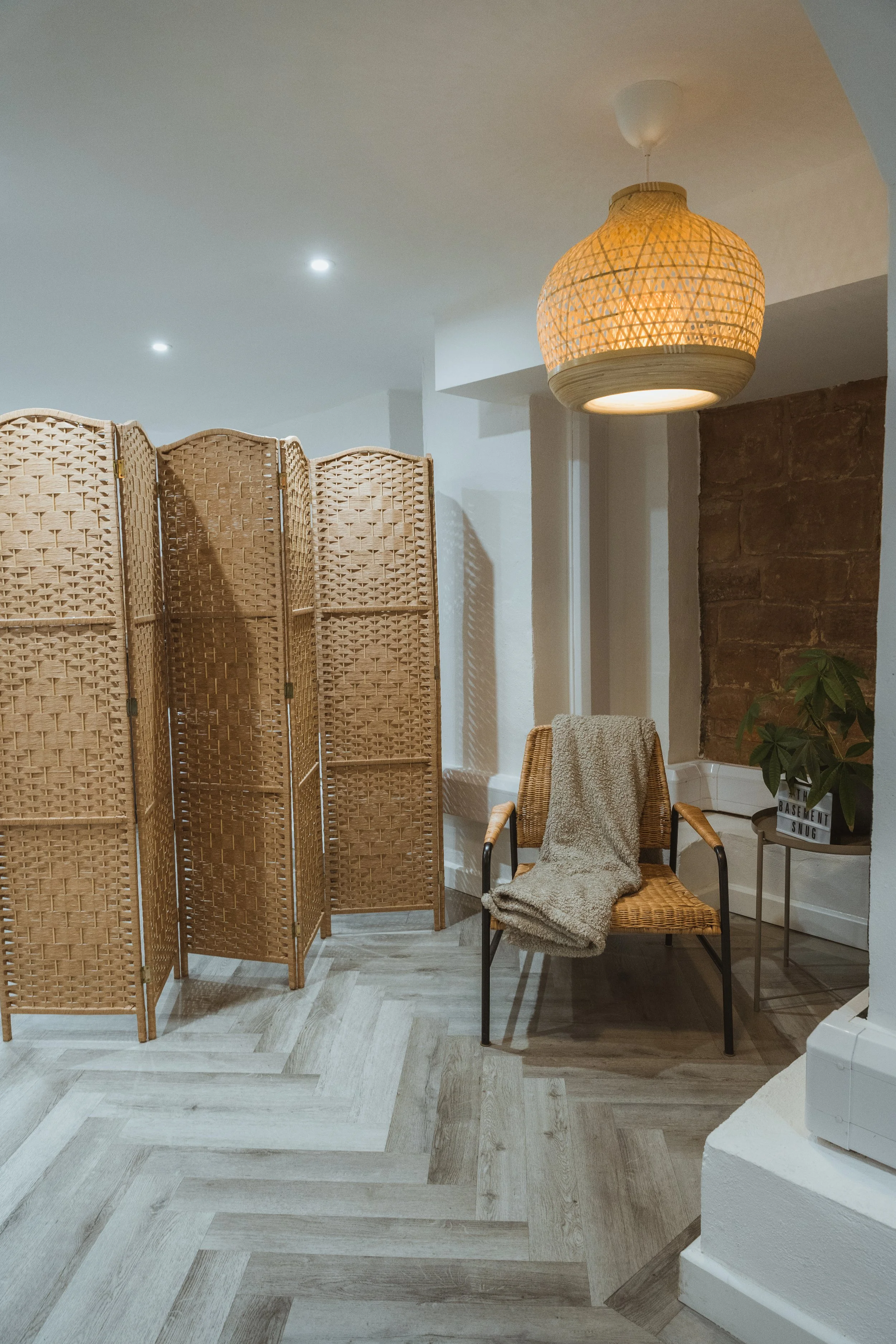 Interior of a yoga studio and event space with woven wicker folding room divider, beige armchair with a throw blanket. Kenilworth, Warwickshire