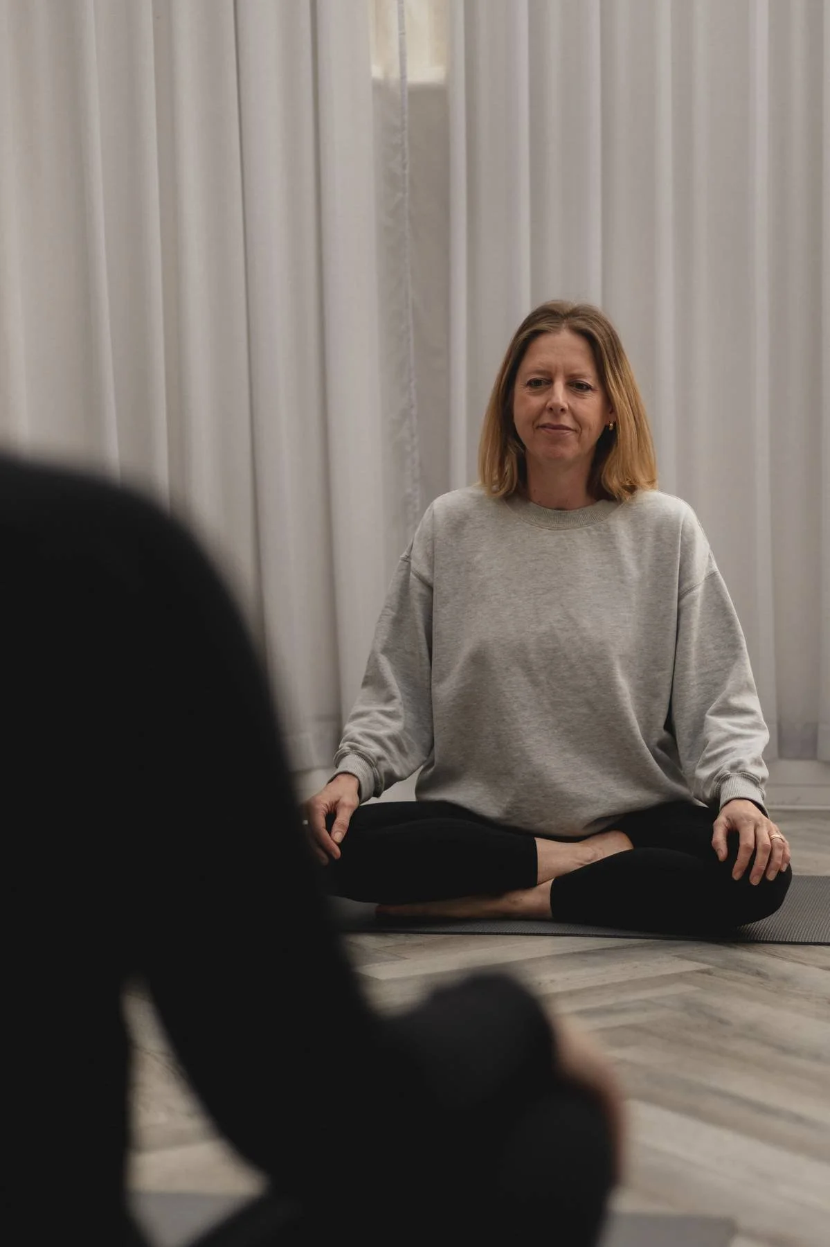 Woman practicing meditation or yoga while sitting cross-legged indoors, at a Kenilworth yoga studio class