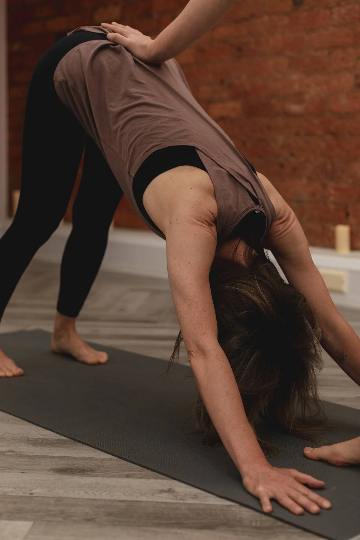 A woman practicing yoga in downward dog pose on a yoga mat indoors at a Kenilworth yoga studio class.