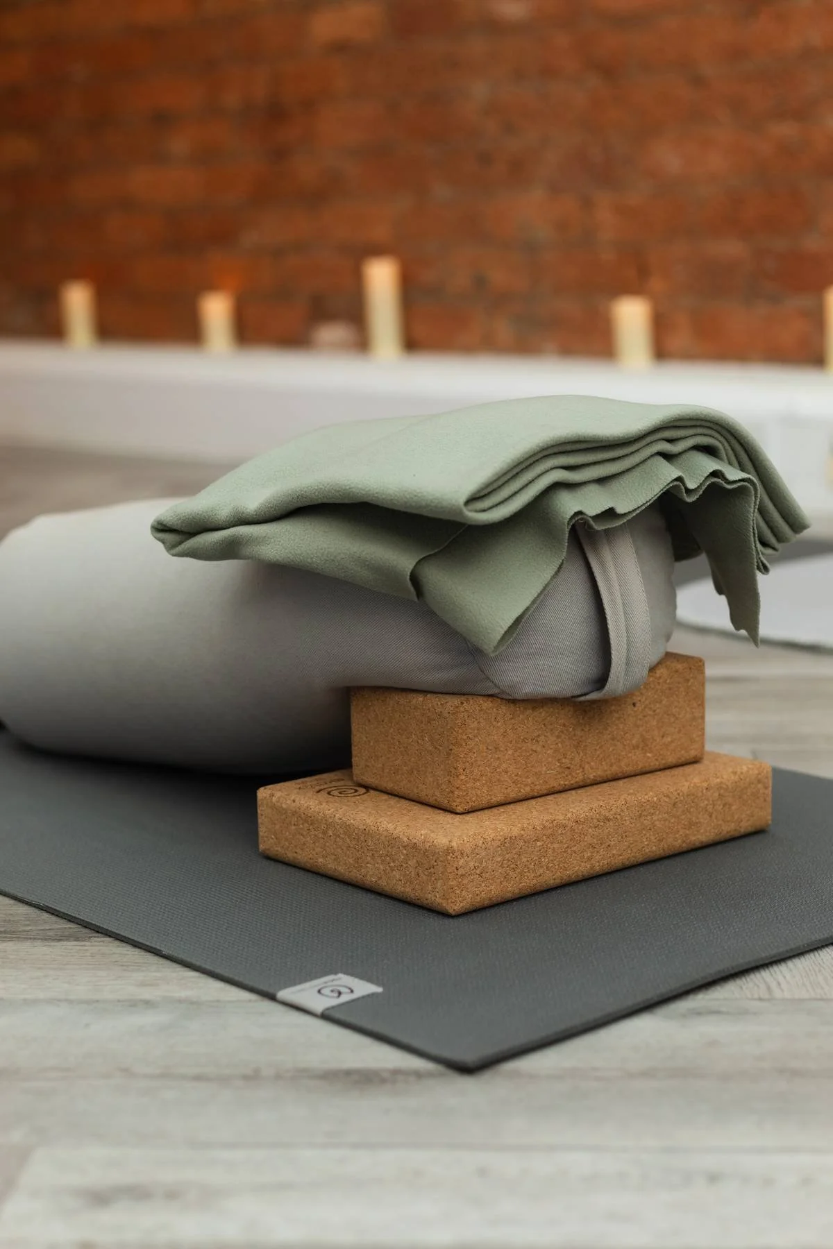 A folded green cloth resting on a gray yoga block, placed on a cork yoga block at The Basement Snug Yoga Studio in Kenilworth.