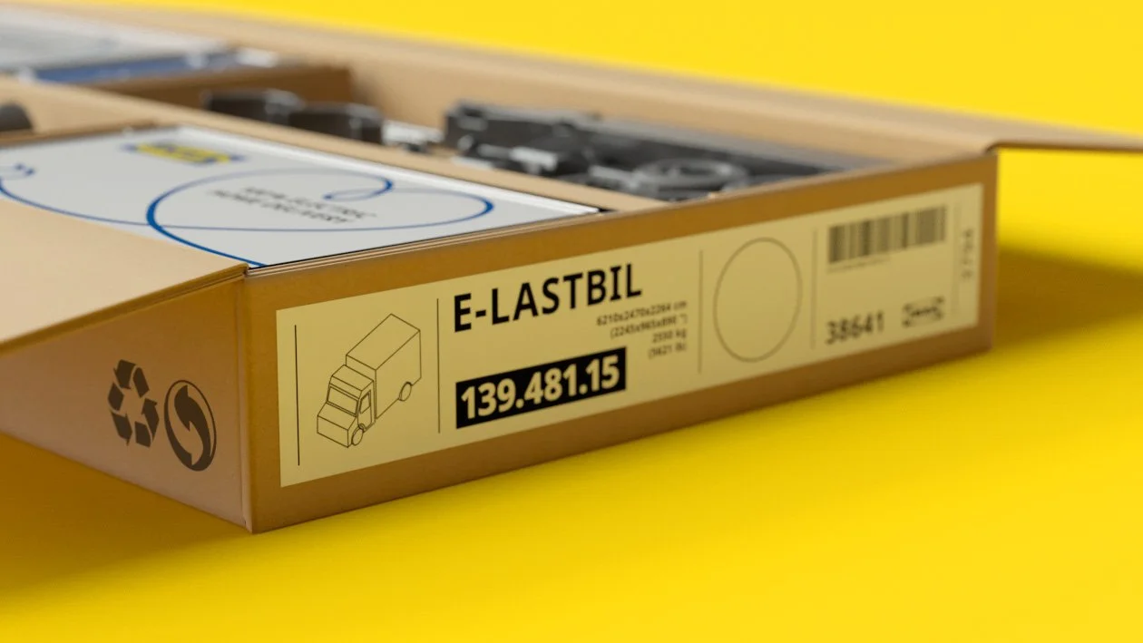 A cardboard box with a label that reads "E-LASTBIL" and a number "139.481.15." The box contains parts for a model truck, with visible black and gray parts inside. The background is yellow.