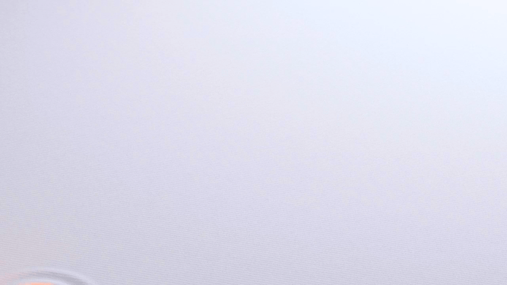 A mostly blank, light-colored surface with some subtle lines and a small, round object in the bottom left corner.