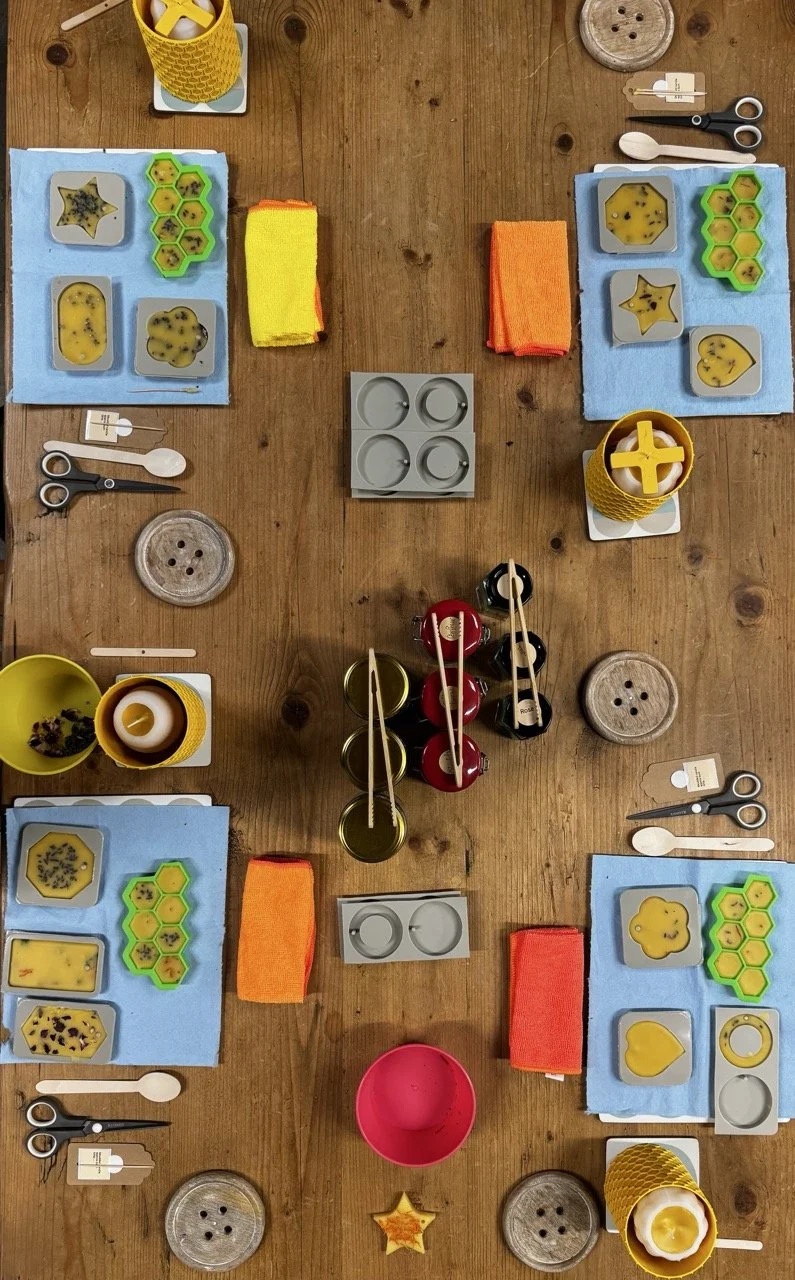A table set for four with blue placemats, yellow and orange napkins, various cookie cutters, utensils, and fruit preserves.