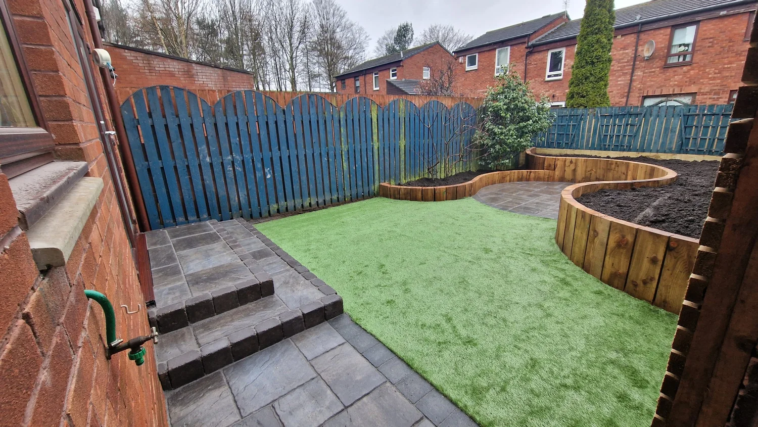 Curved timber sleeper raised beds within a landscaped garden
