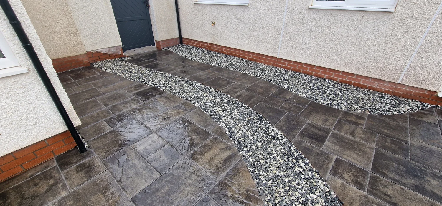 Concrete paved patio with decorative gravel borders installed by Team Bespoke