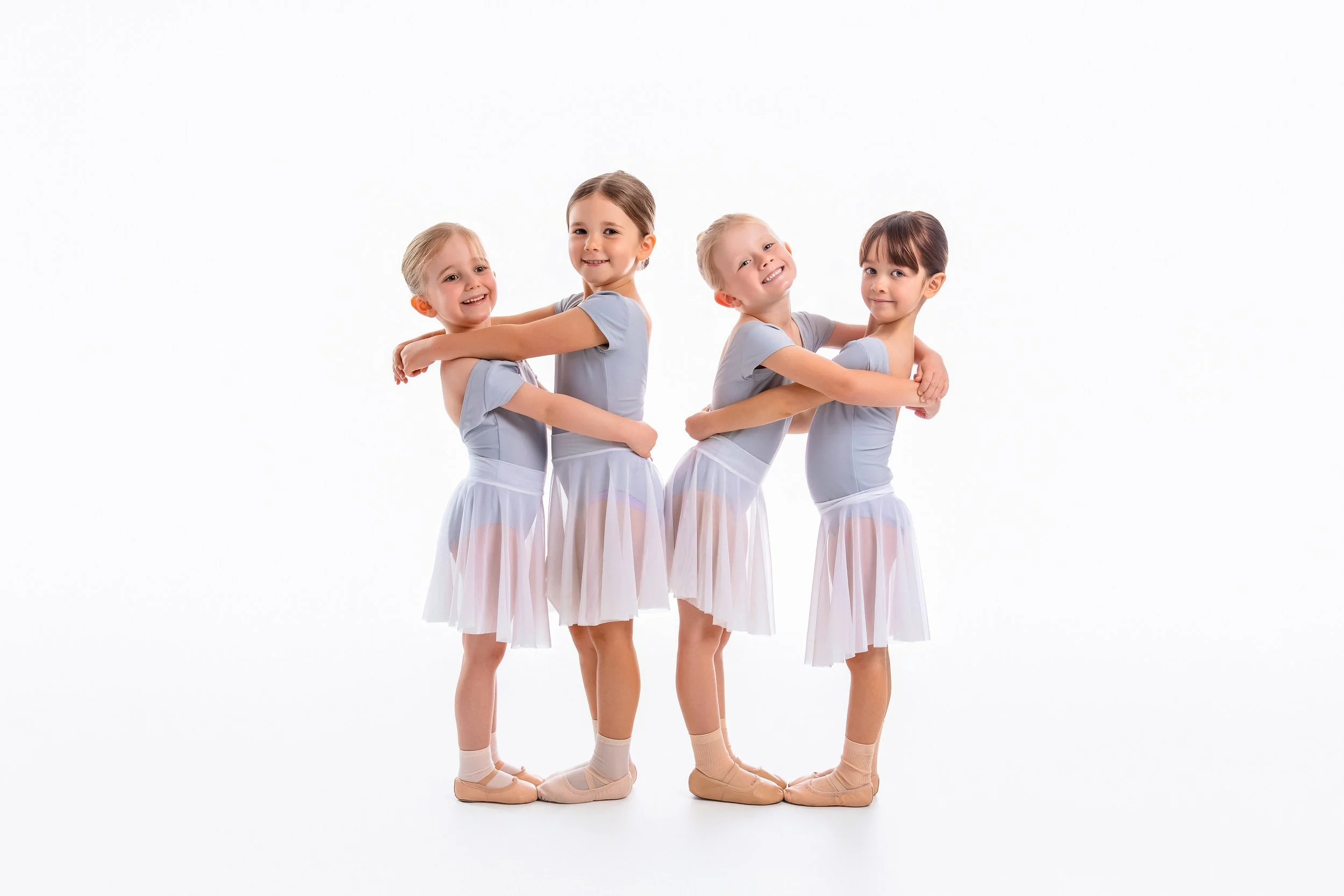 Four young ballet dancers posing together in their ballet uniforms at Shire Ballet Academy