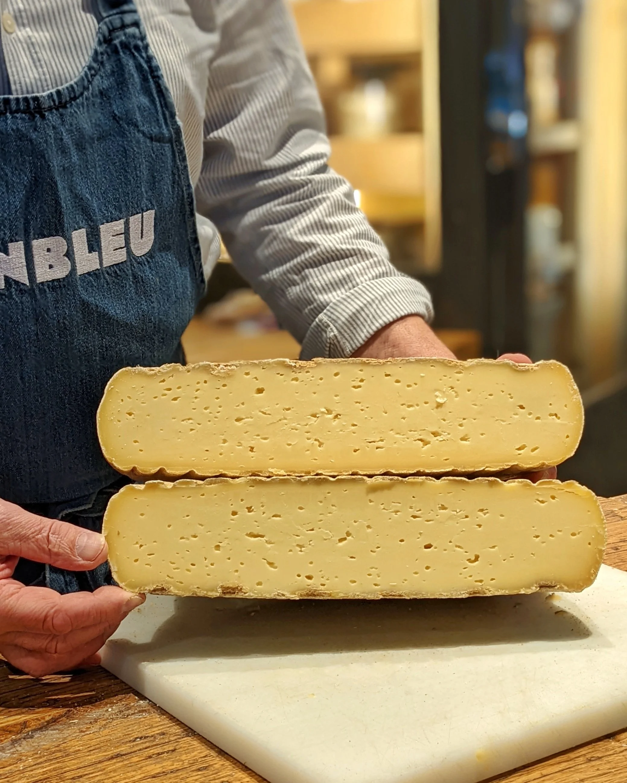Deux gros morceaux de fromage coupé en deux, tenu par un fromager
