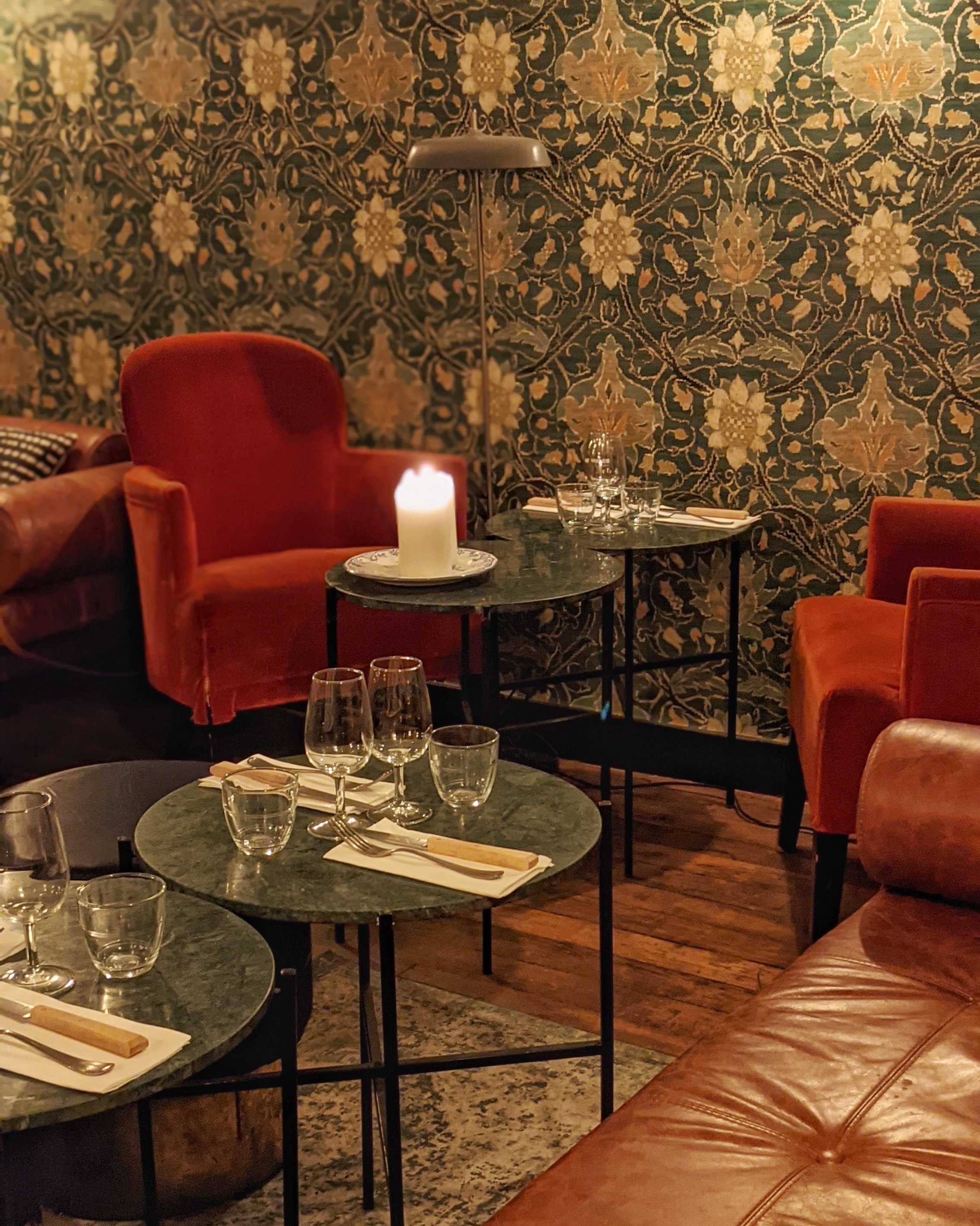 Salon intimiste du restaurant MONBLEU Le Comptoir à Paris 3e, avec fauteuils en velours rouge, tables dressées et décoration florale, disponible pour privatiser.
