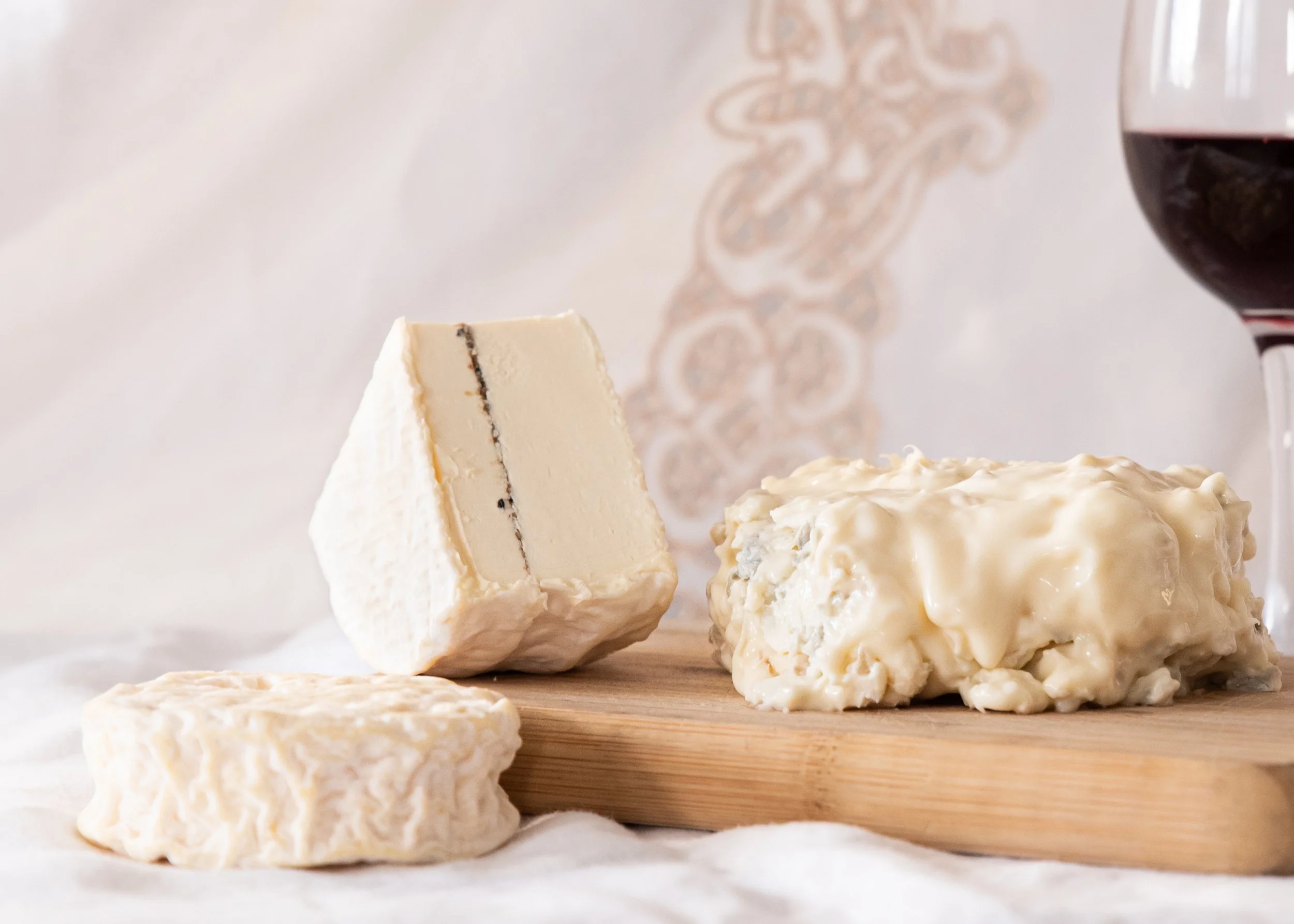 Présentation de 3 fromages avec un verre de vin rouge à droite
