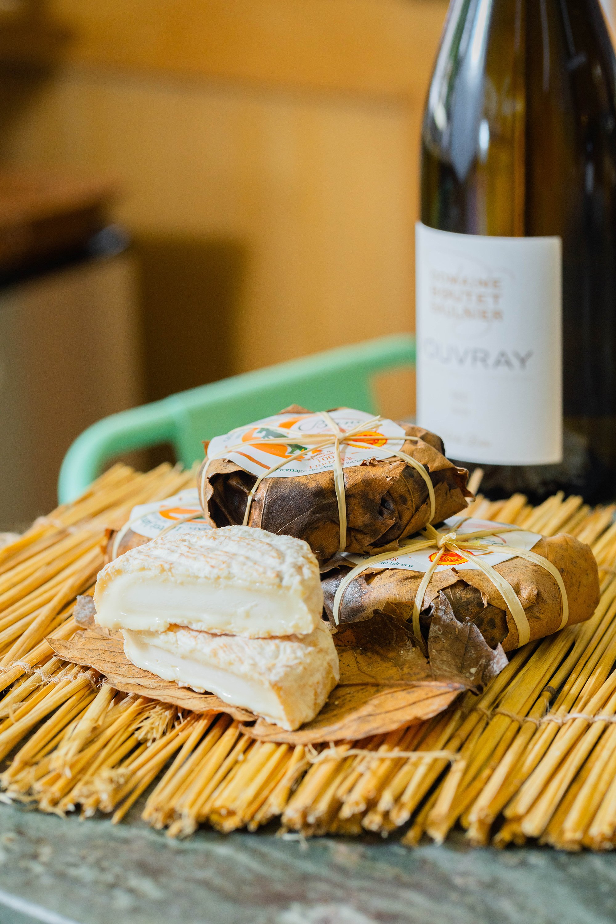 Présentation de plusieurs fromages sur une table et une bouteille de vin en fond