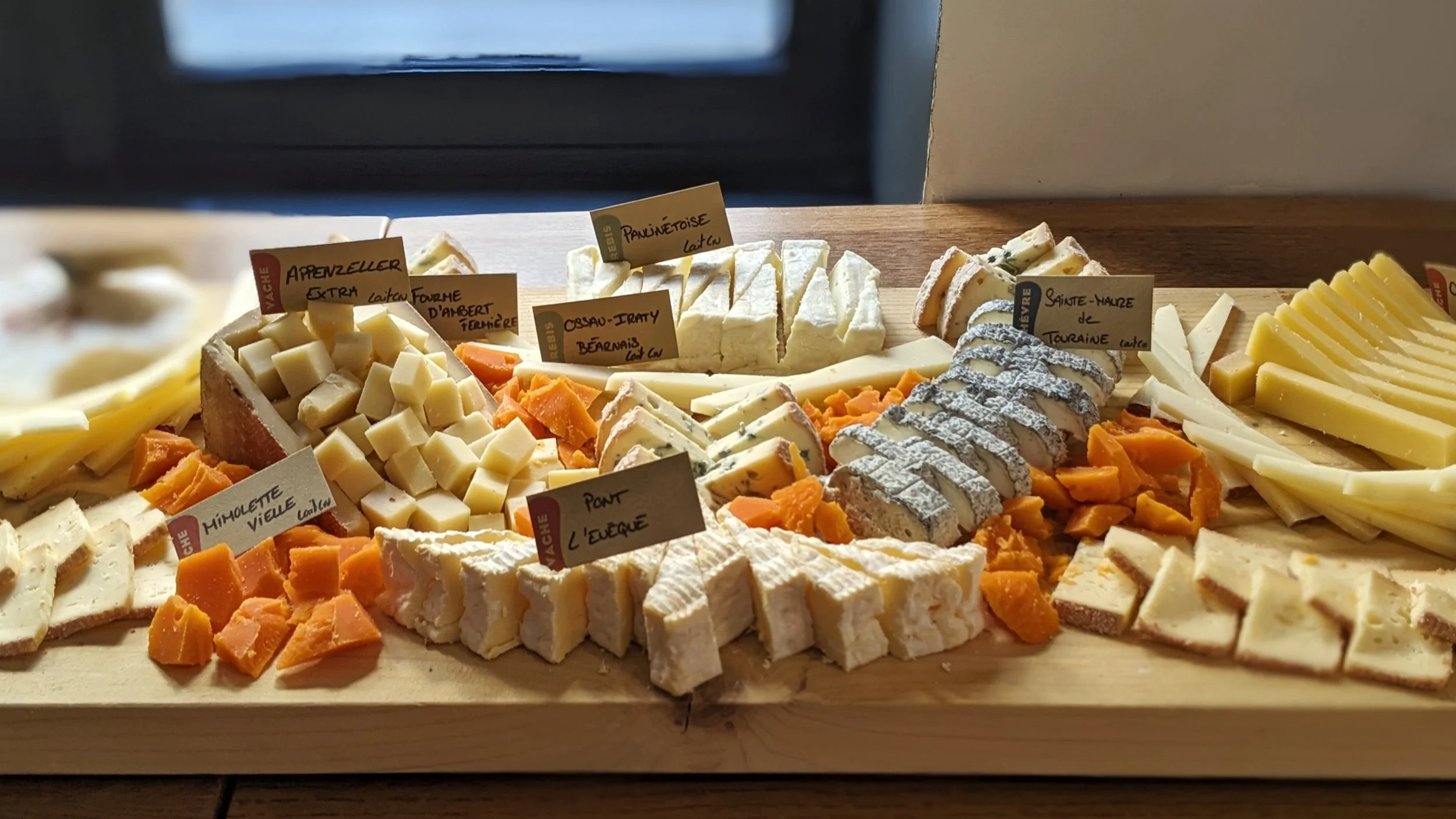 Planche en bois avec plusieurs type de fromage étiqueté 