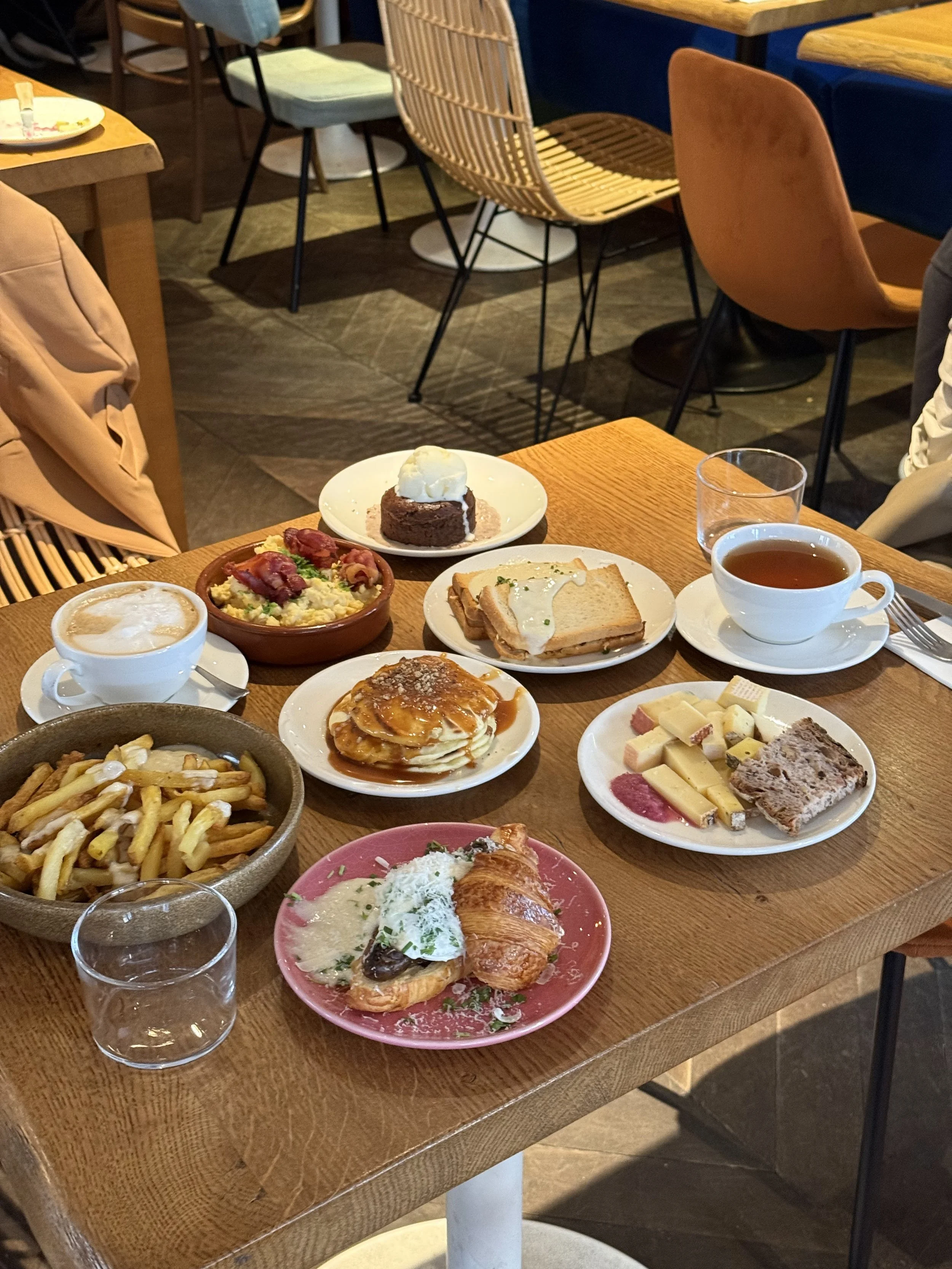 Une table avec plusieurs assiettes sucrés et salé pour le brunch du dimanche, frites, croissants, pains thé, moelleux chocolat, café, oeuf brouillé