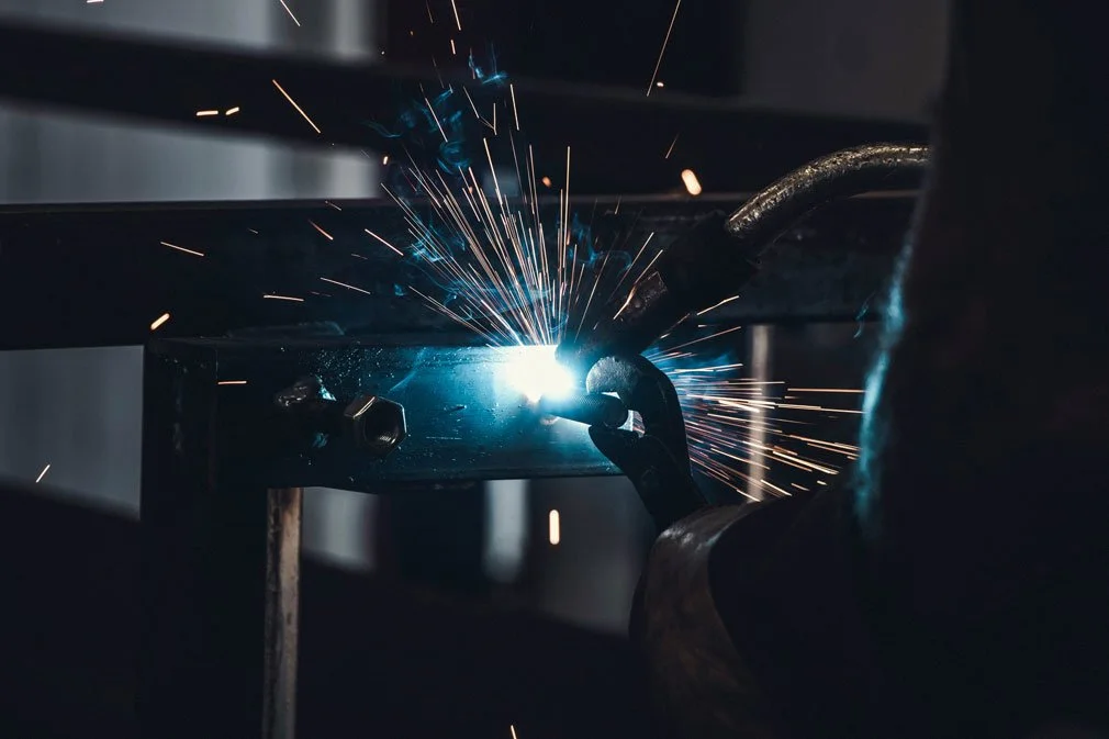 A person welding metal with bright sparks flying around.