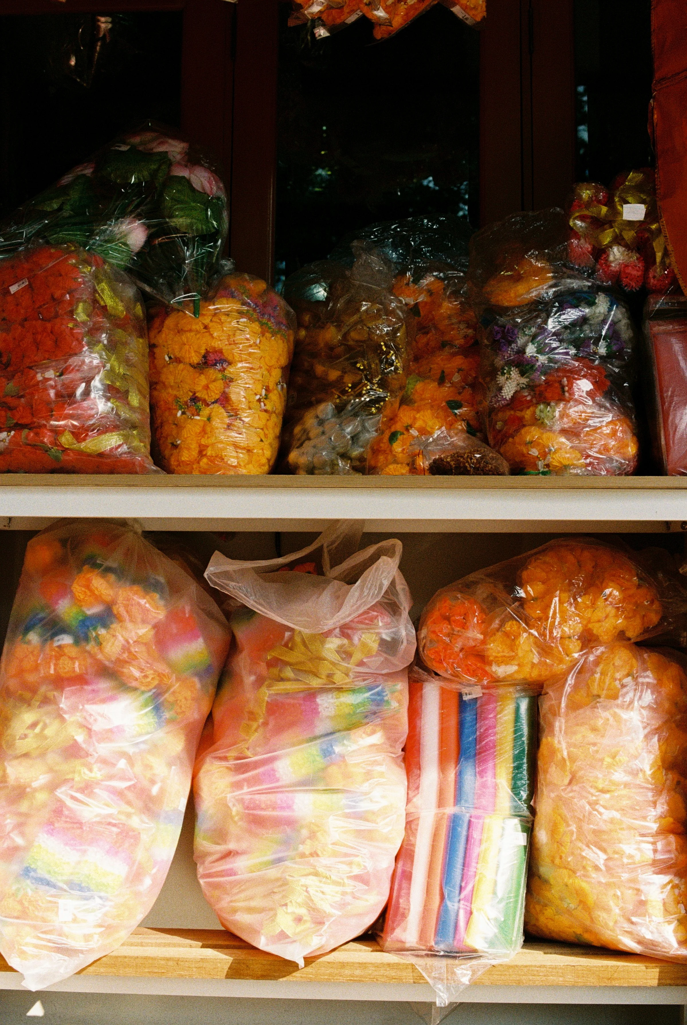 Multiple plastic bags filled with various colorful candies and marshmallows placed on a wooden shelf.