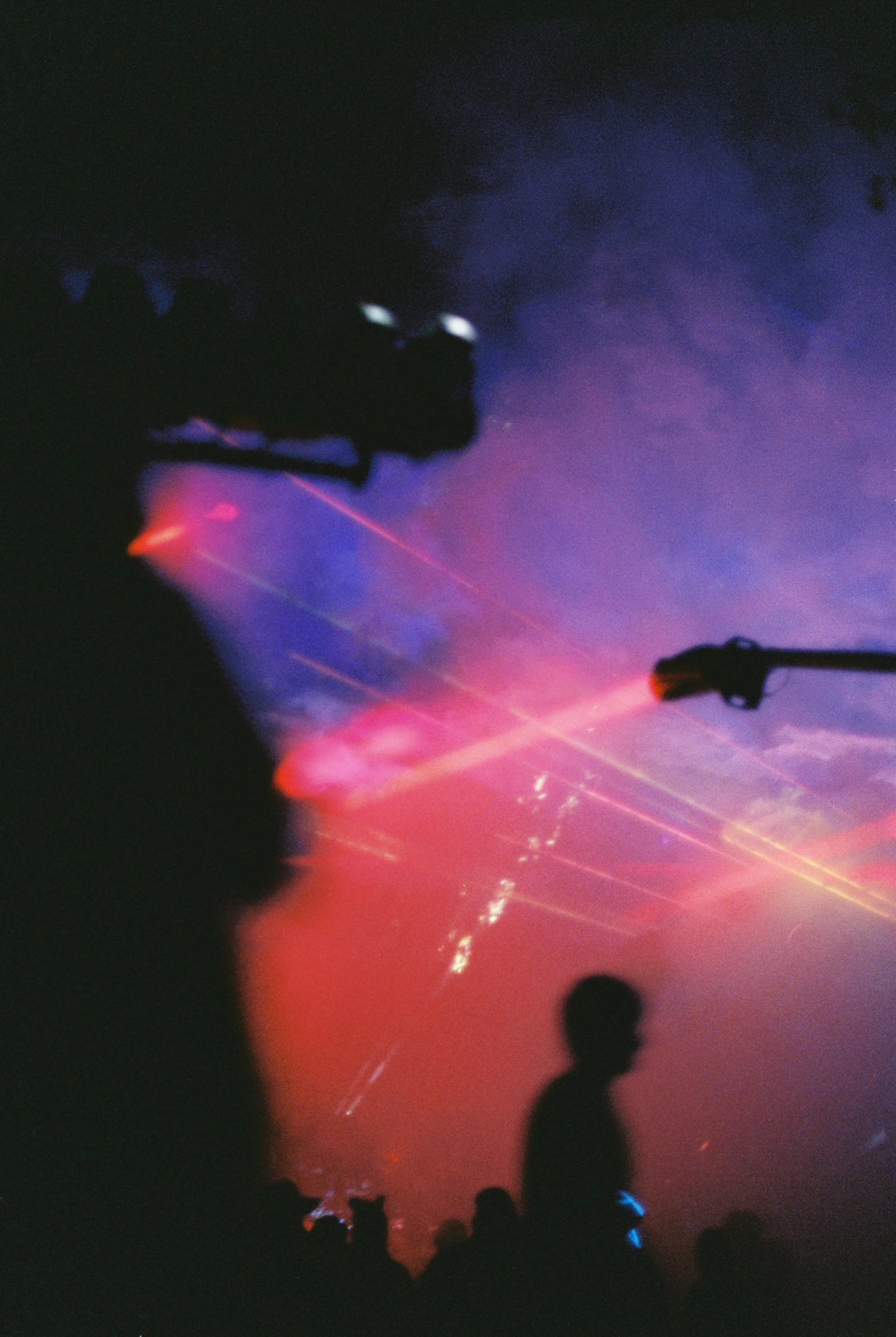 Silhouettes of people watching fireworks against a colorful night sky with purple, pink, and orange hues.