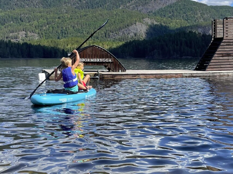 Barn som padler på SUP foran flytebrygge i vannet på Garvikstrondi camping