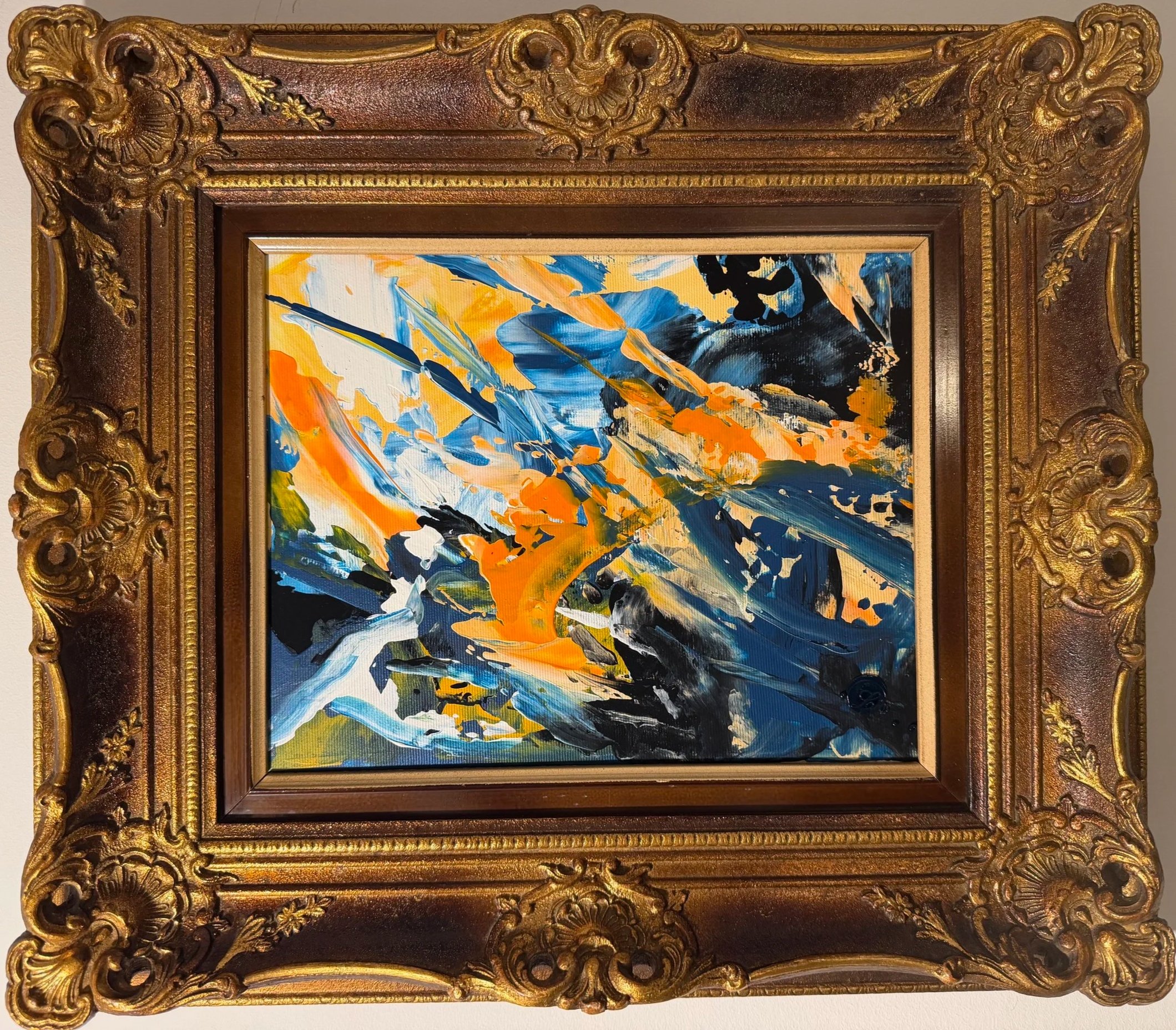 Abstraktes Gemälde mit dynamischen Farbflächen in Orange, Blau, dem schwärzesten Schwarz und Weiß, präsentiert in einem ornamentalen barocken Goldrahmen.