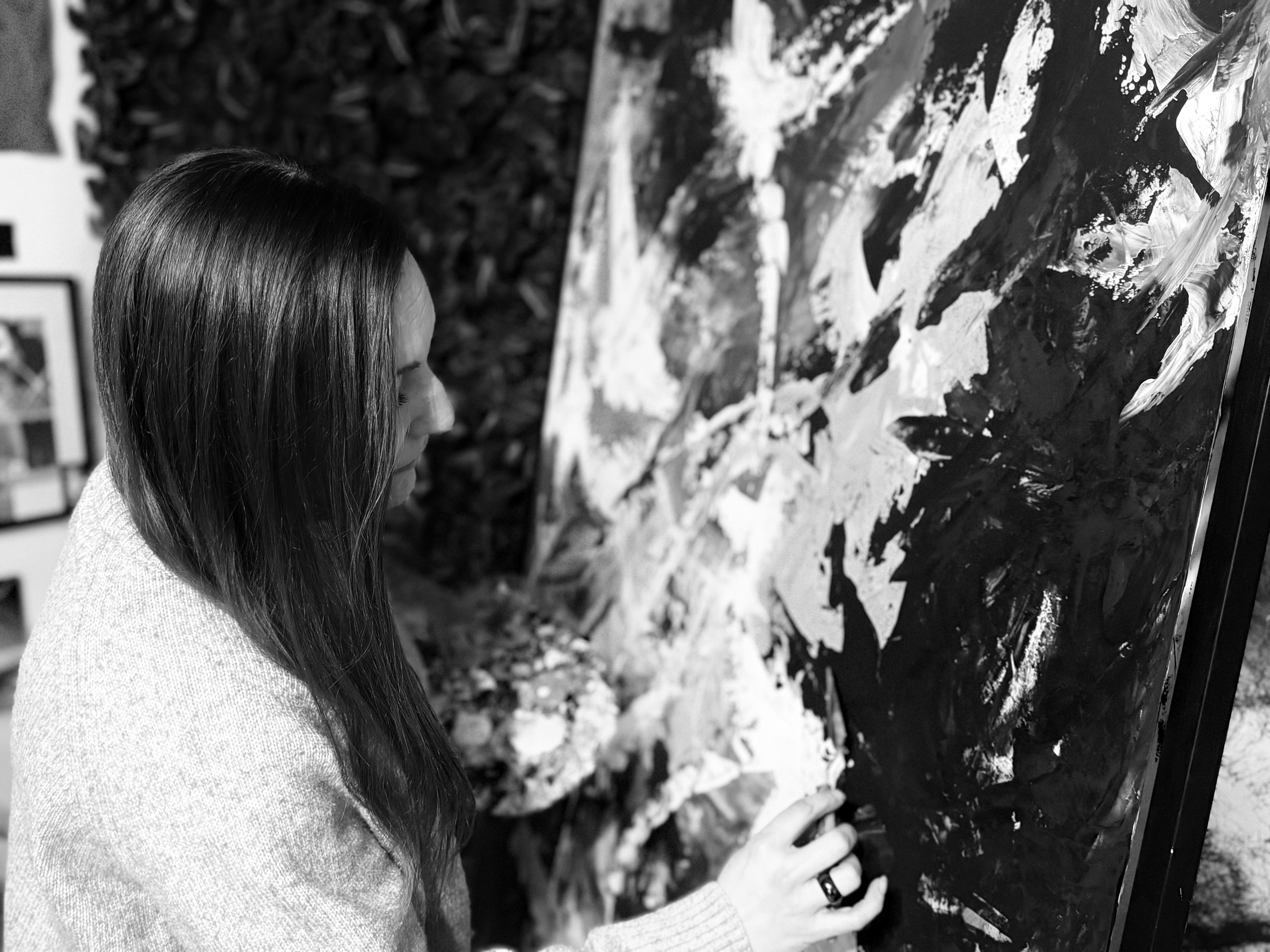 Schwarz-Weiß-Fotografie von Anne Lilly Lippek im Atelier beim fertigen eines Gemäldes auf der Staffelei.