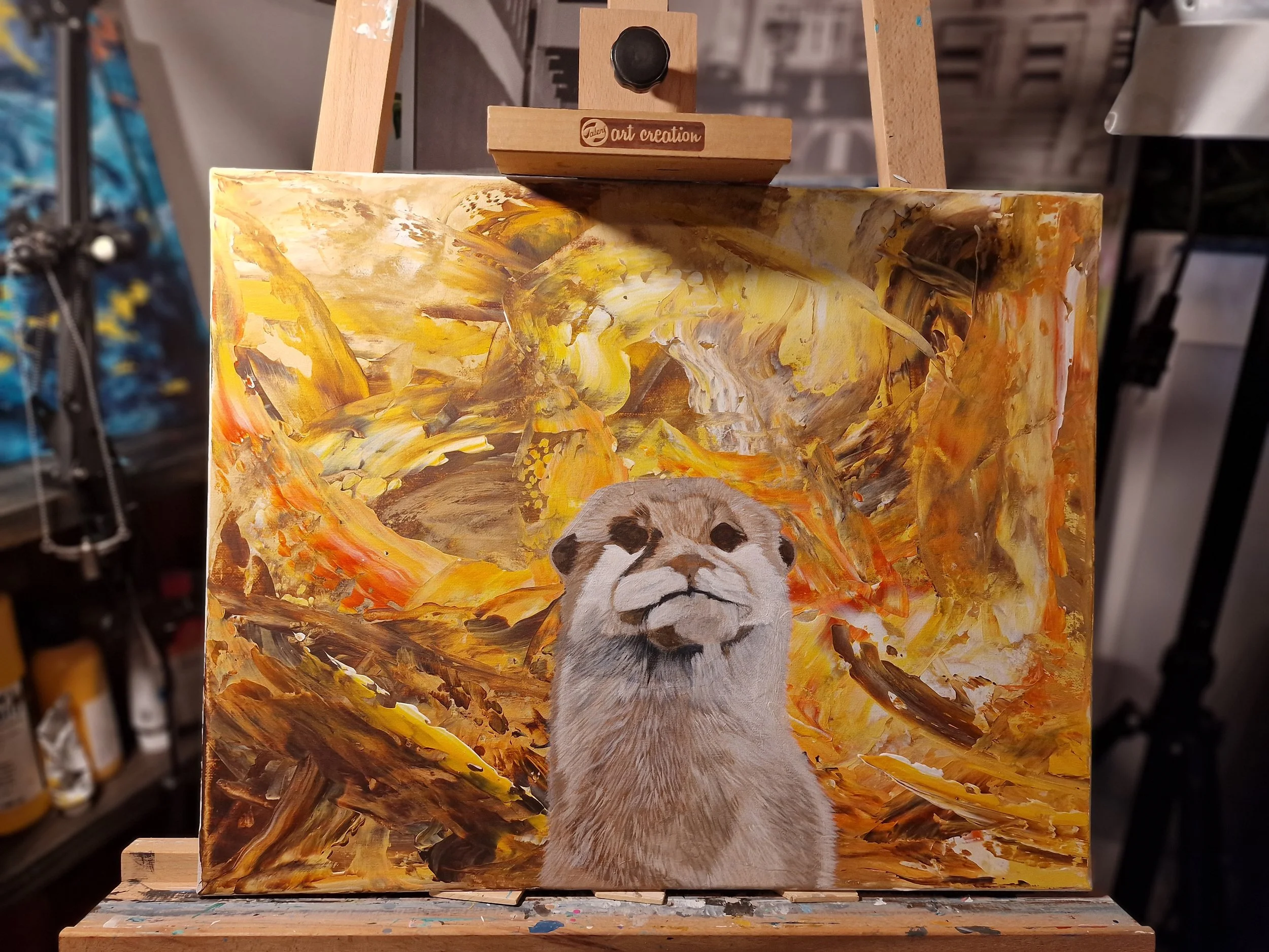Gemälde eines Otters vor einem warmen, abstrakten Hintergrund in Gelb-, Orange- und Brauntönen, präsentiert auf einer Staffelei.