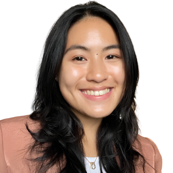 A woman with long black hair smiling at the camera, wearing a brown blazer and a white top, against a white background.