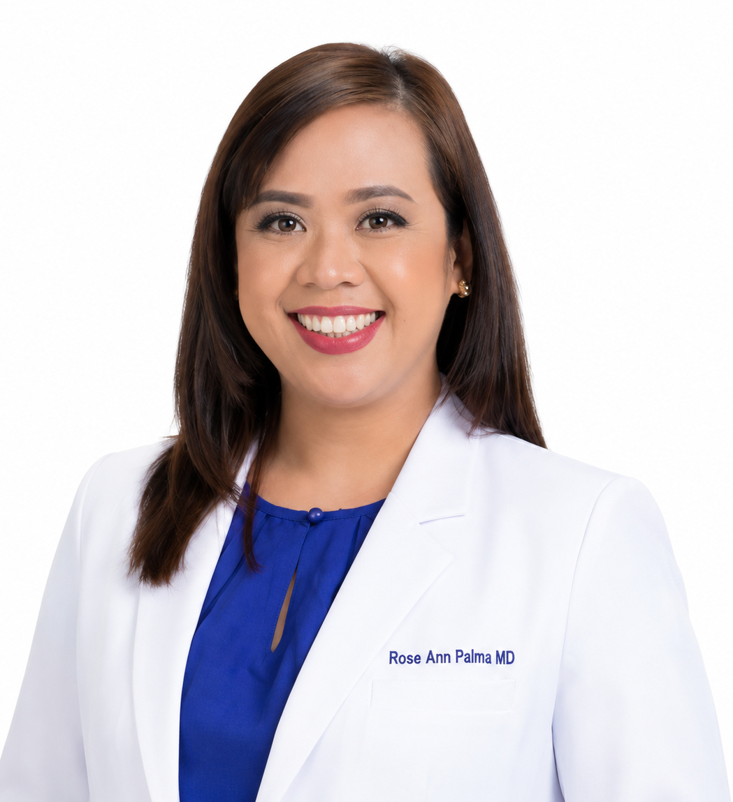 Professional portrait of Dr. Rose Ann Palma, wearing a white coat with her name embroidered, smiling against a plain white background.