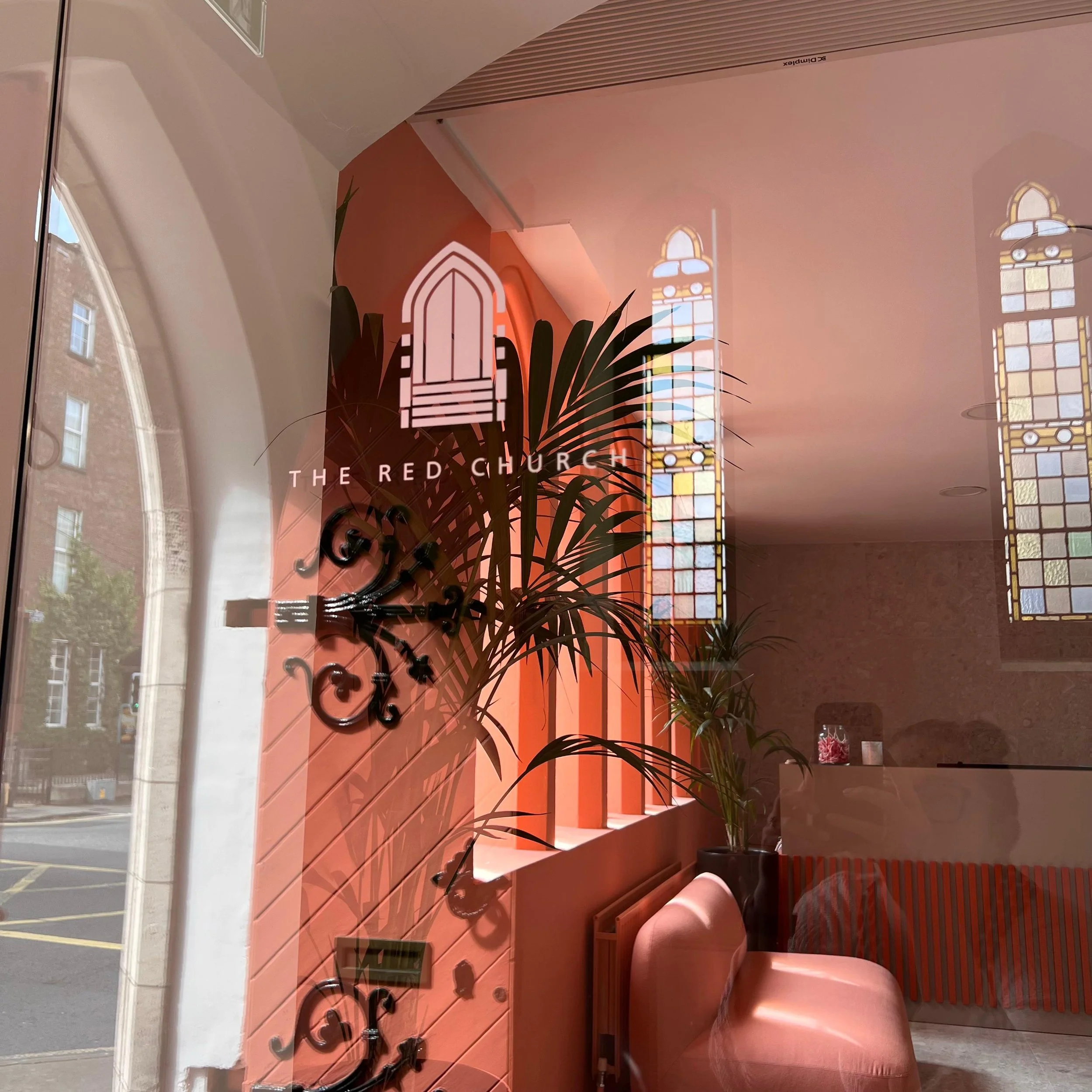 Interior view of an old church converted into modern office space with bold colours, stained glass windows, a elevated office space throughout.