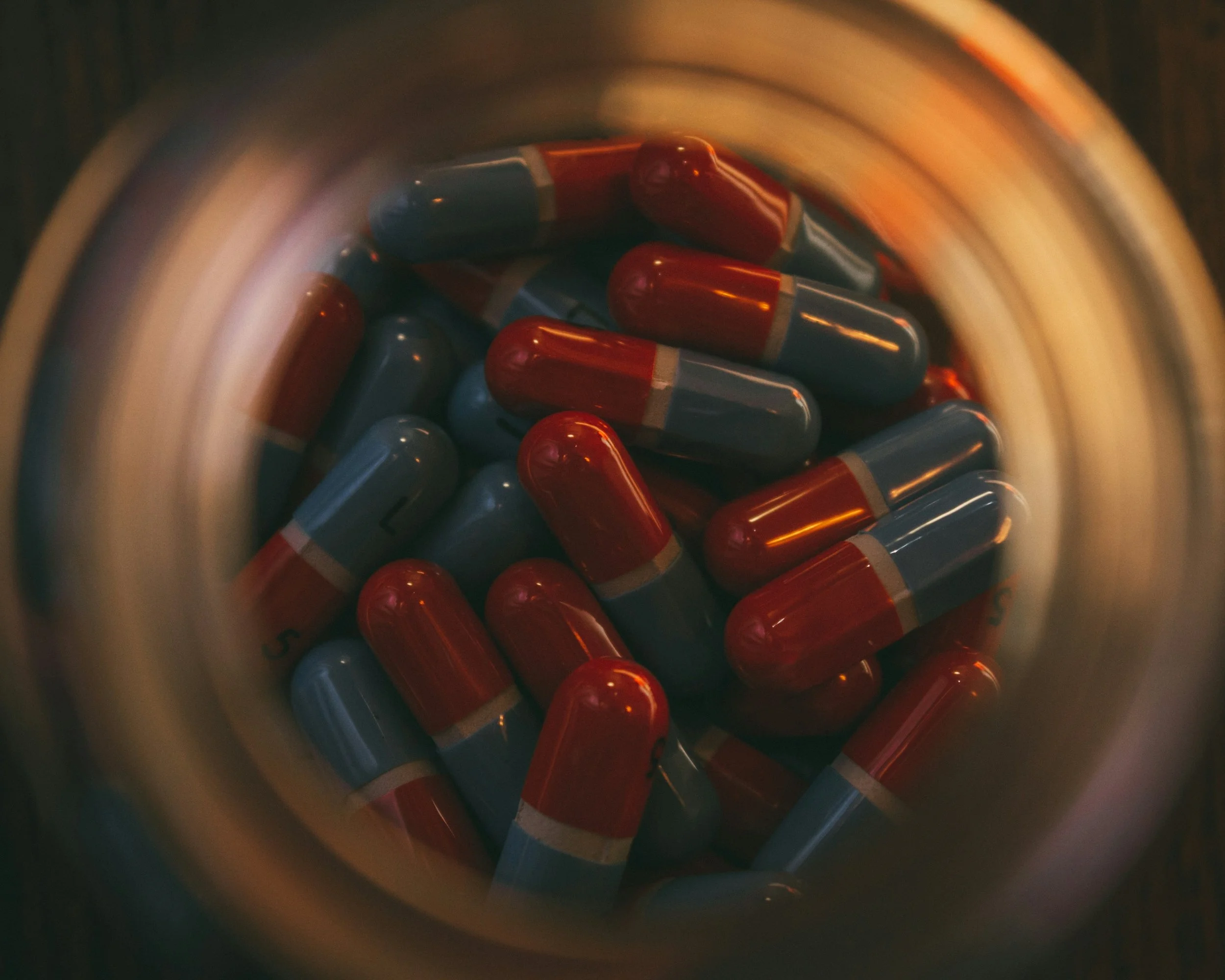 Close-up of red and blue capsules inside a container with a circular motion blur effect.