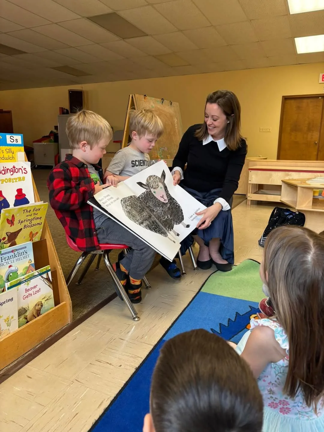 Ms. Grace reading to a classroom, assisted by twin students