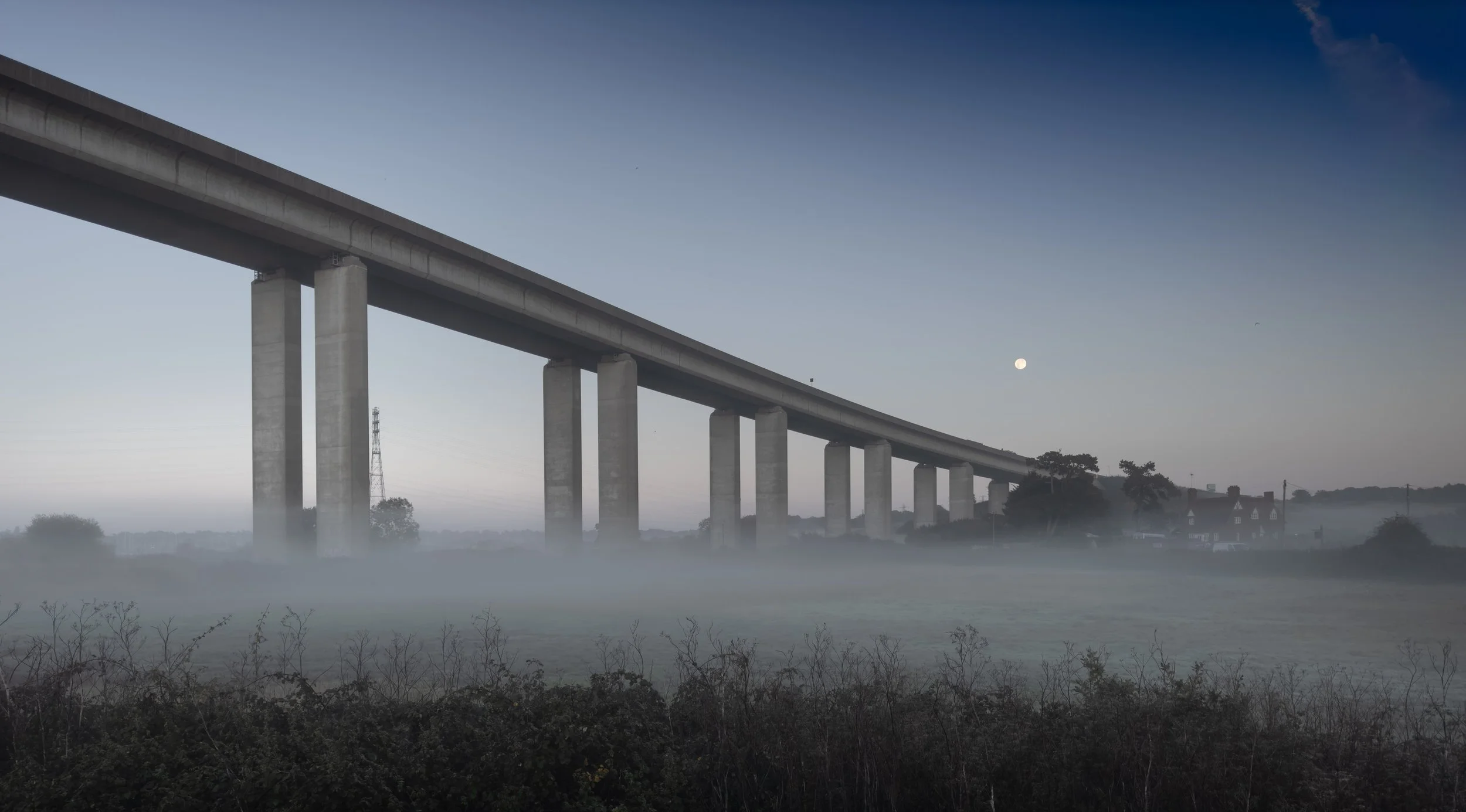 A long concrete bridge spanning a misty landscape, representing the bridge between complex life science technology and user adoption.