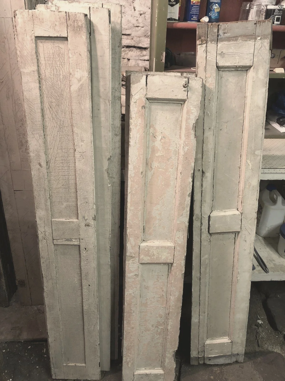 A collection of reclaimed shutters with layers of old paint, before restoration