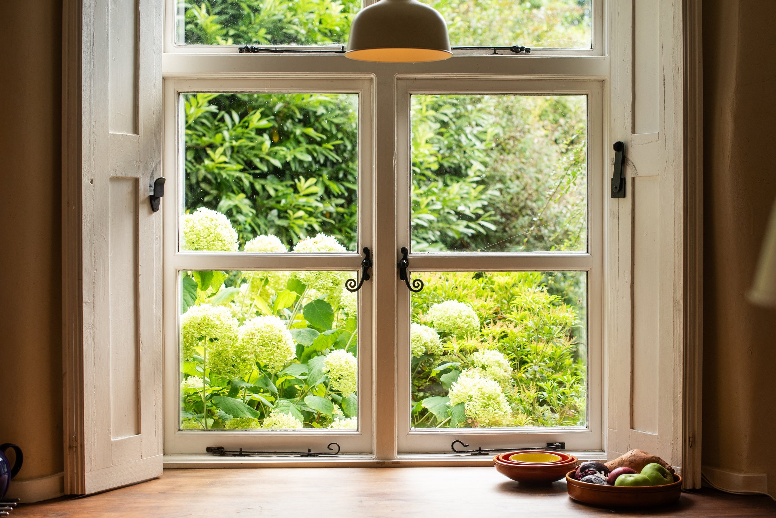 Restored reclaimed shutters folded back from a kitchen window in a 17th-century Cumbrian farmhouse