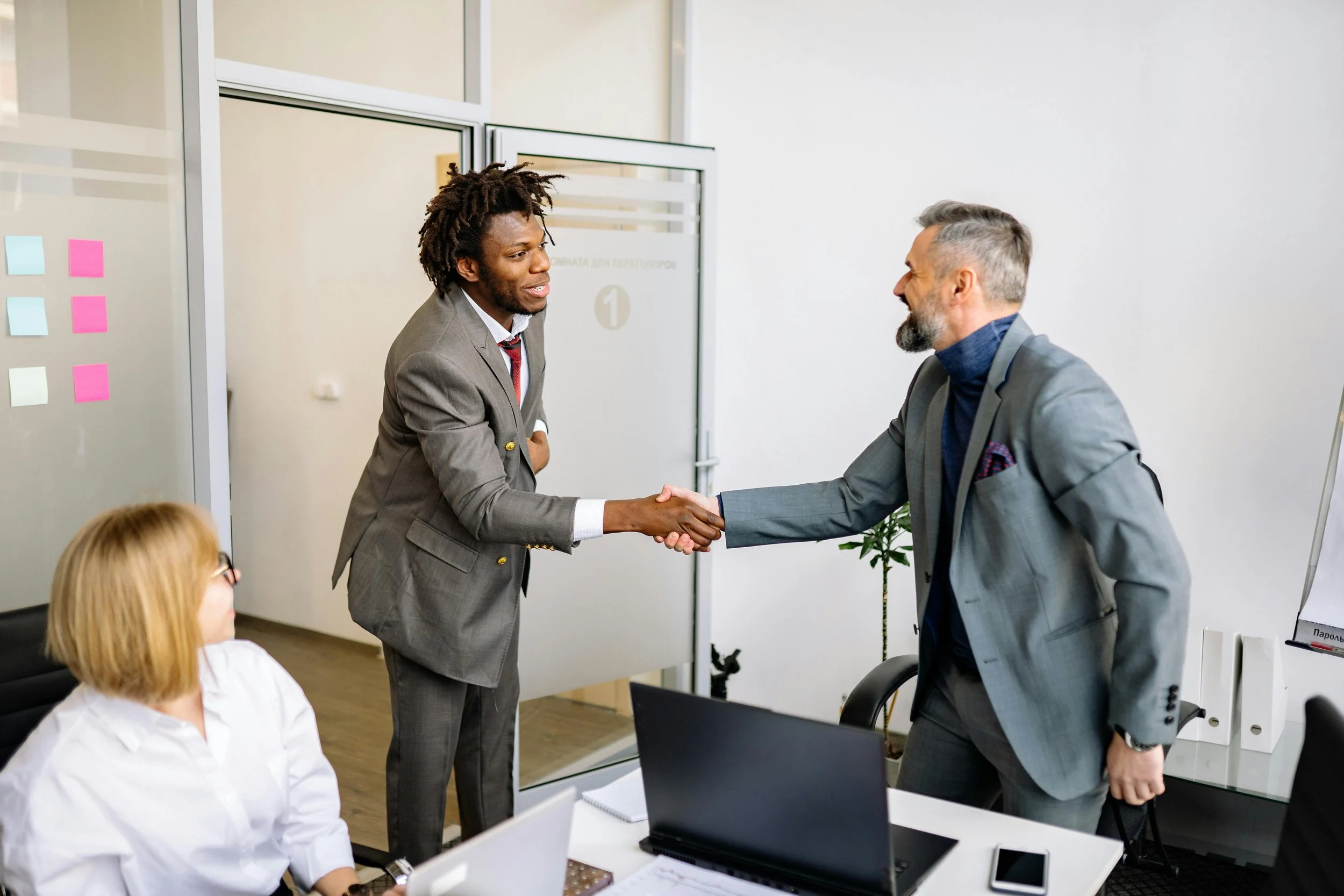 Businessmen giving one another a handshake and smiling