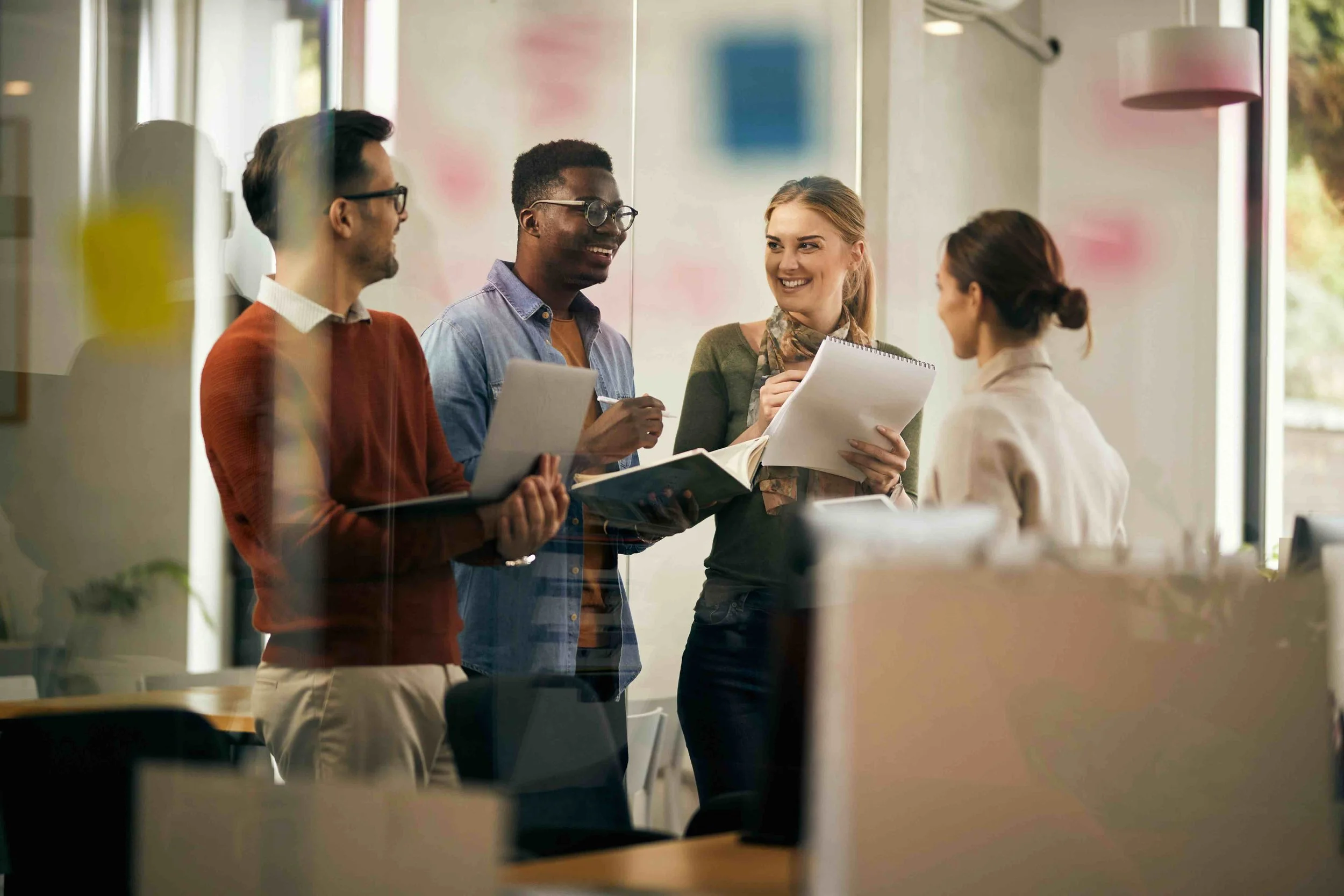 Team of two men and two women standing and talking together in a business setting