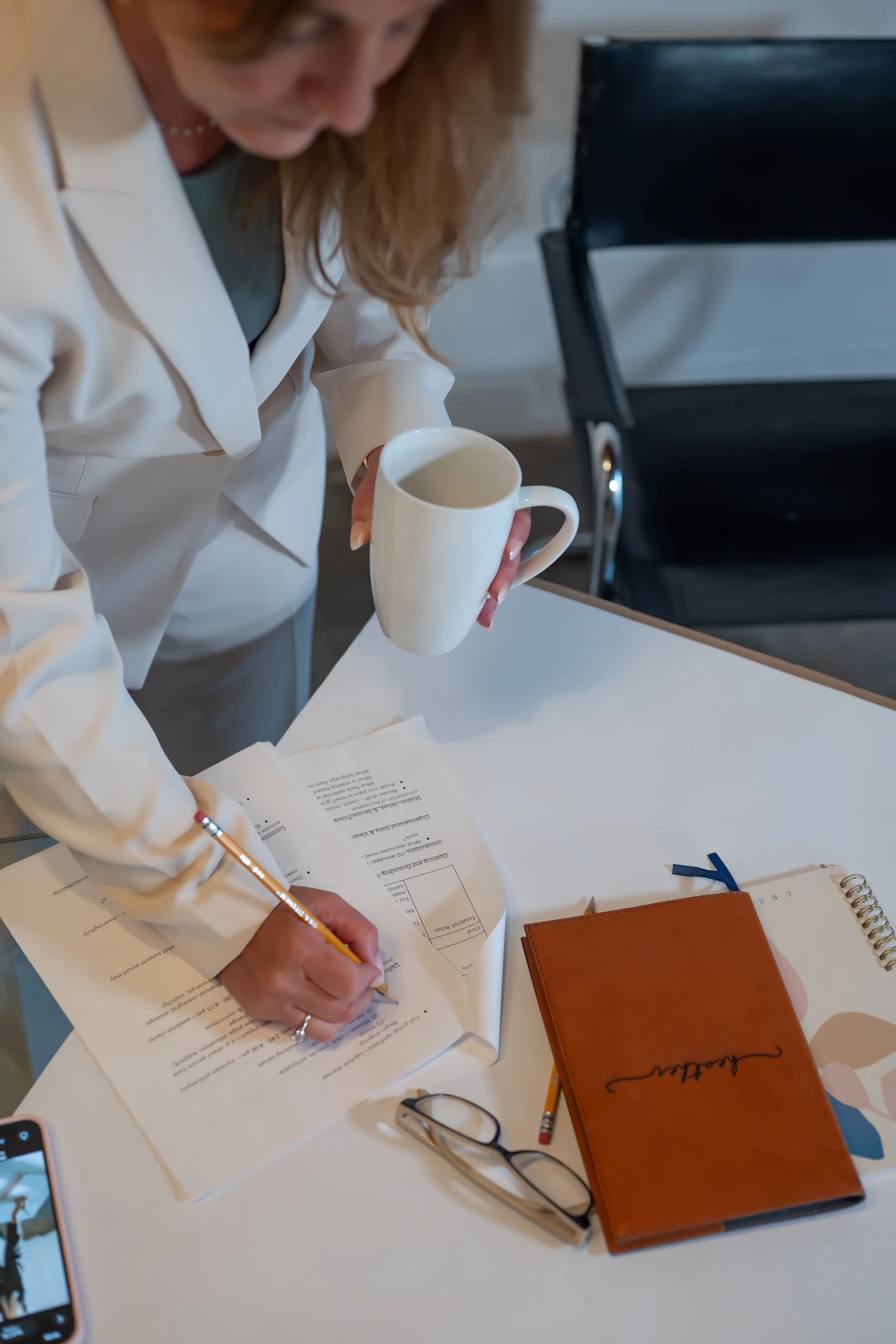 Business woman crossing off a checklist while holding cup of coffee