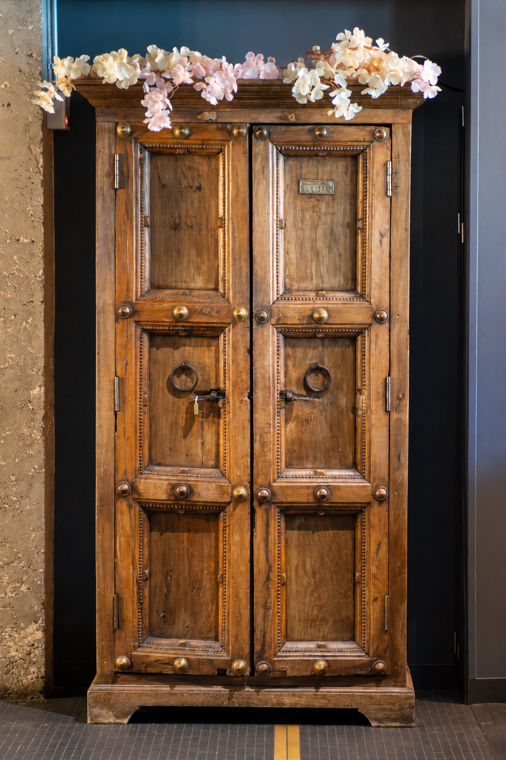 Une armoire en bois rustique décorée de fleurs blanches et roses en haut.