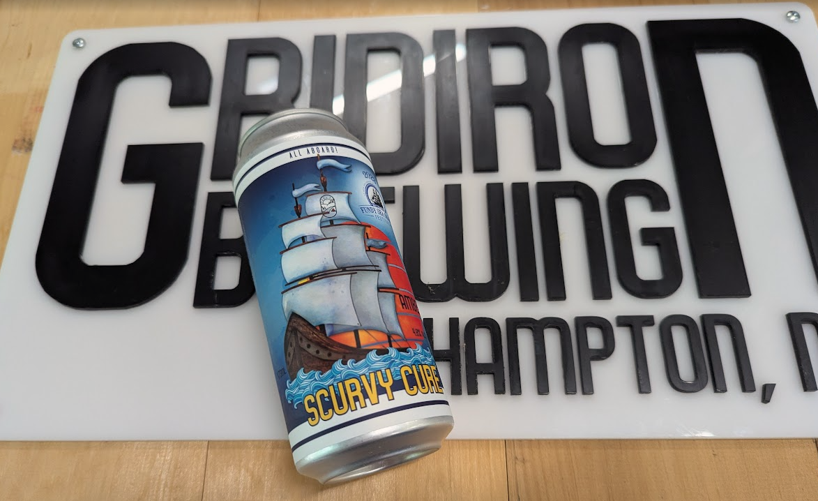 A can of Scurvy Cure beverage resting on a sign that reads 'GROIR COM' with additional text partially visible beneath.