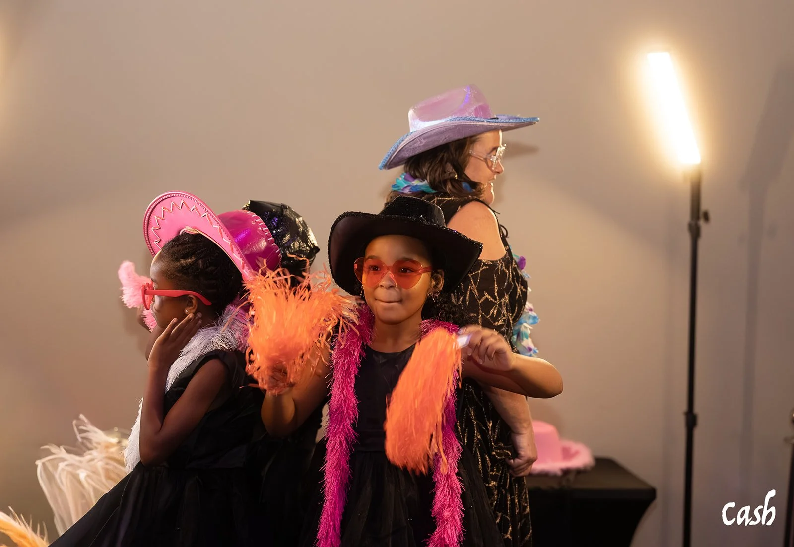 Three children dressed in colorful costumes and hats, posing at a party or event.