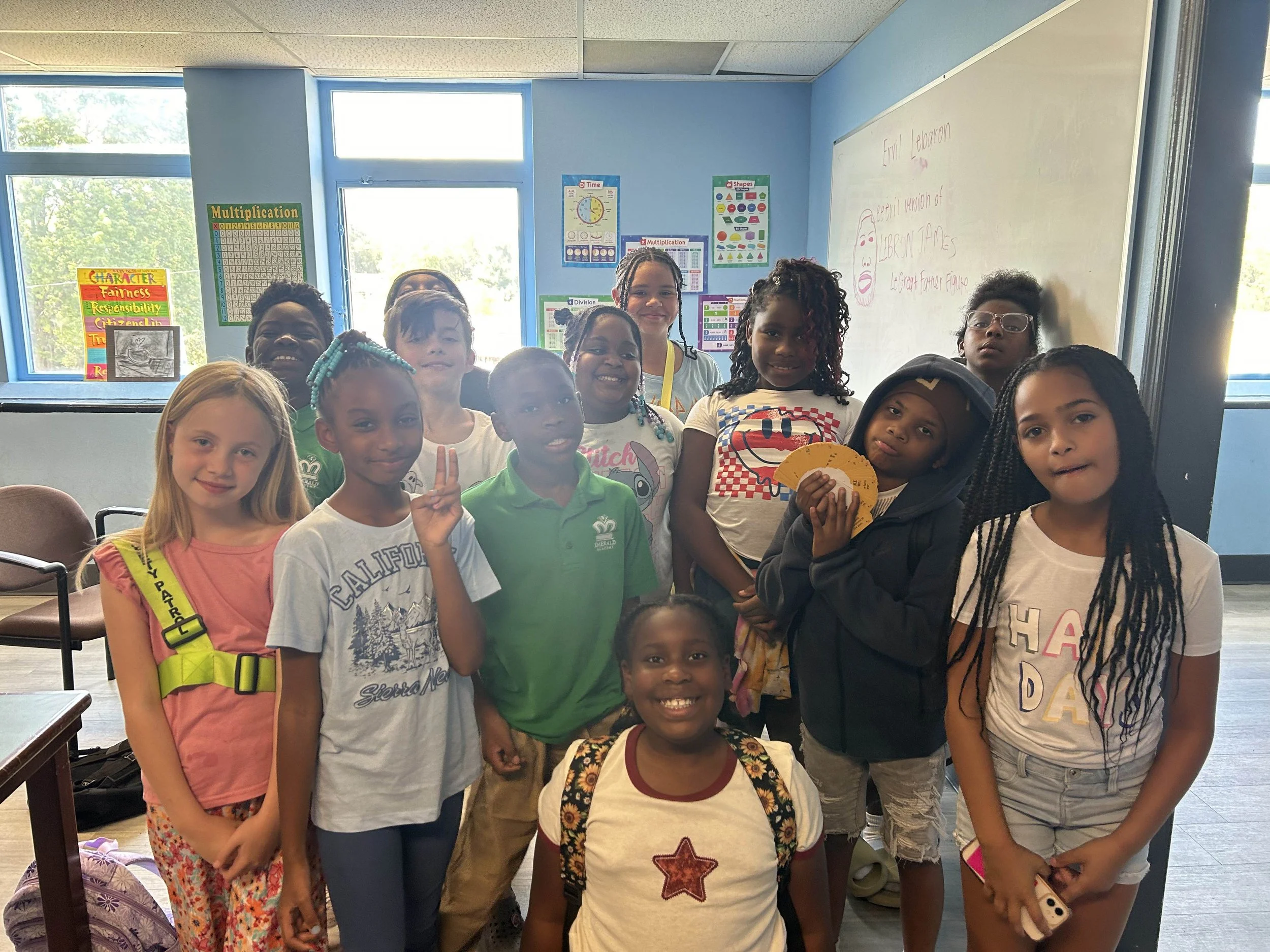 A diverse group of young students smiling and posing together in a classroom.