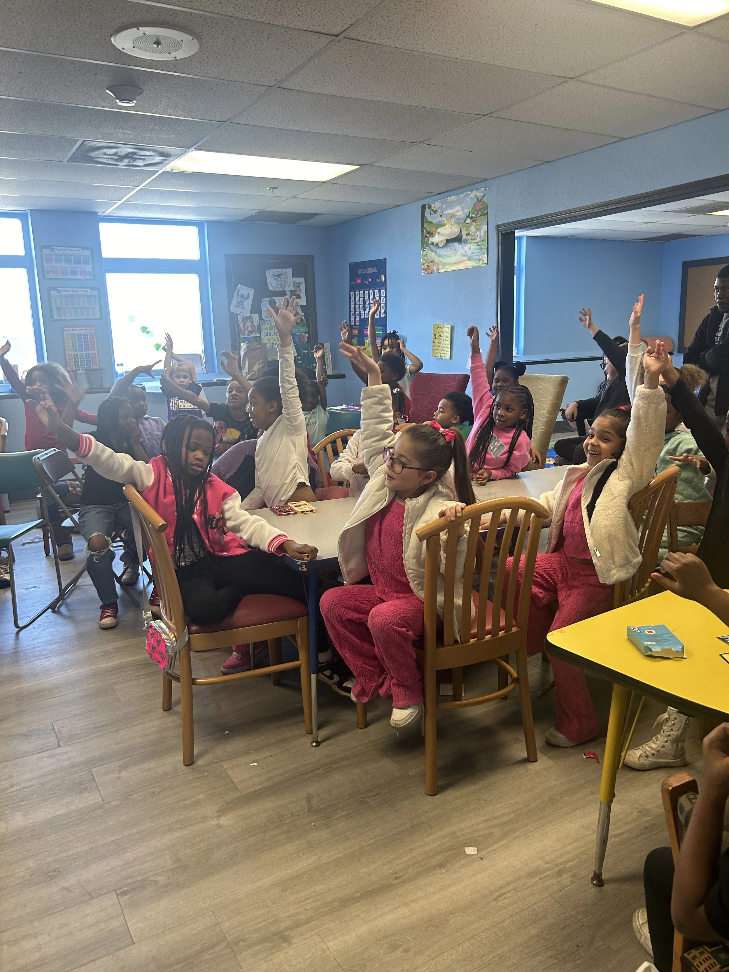 Children in a classroom raising their hands during a lesson.