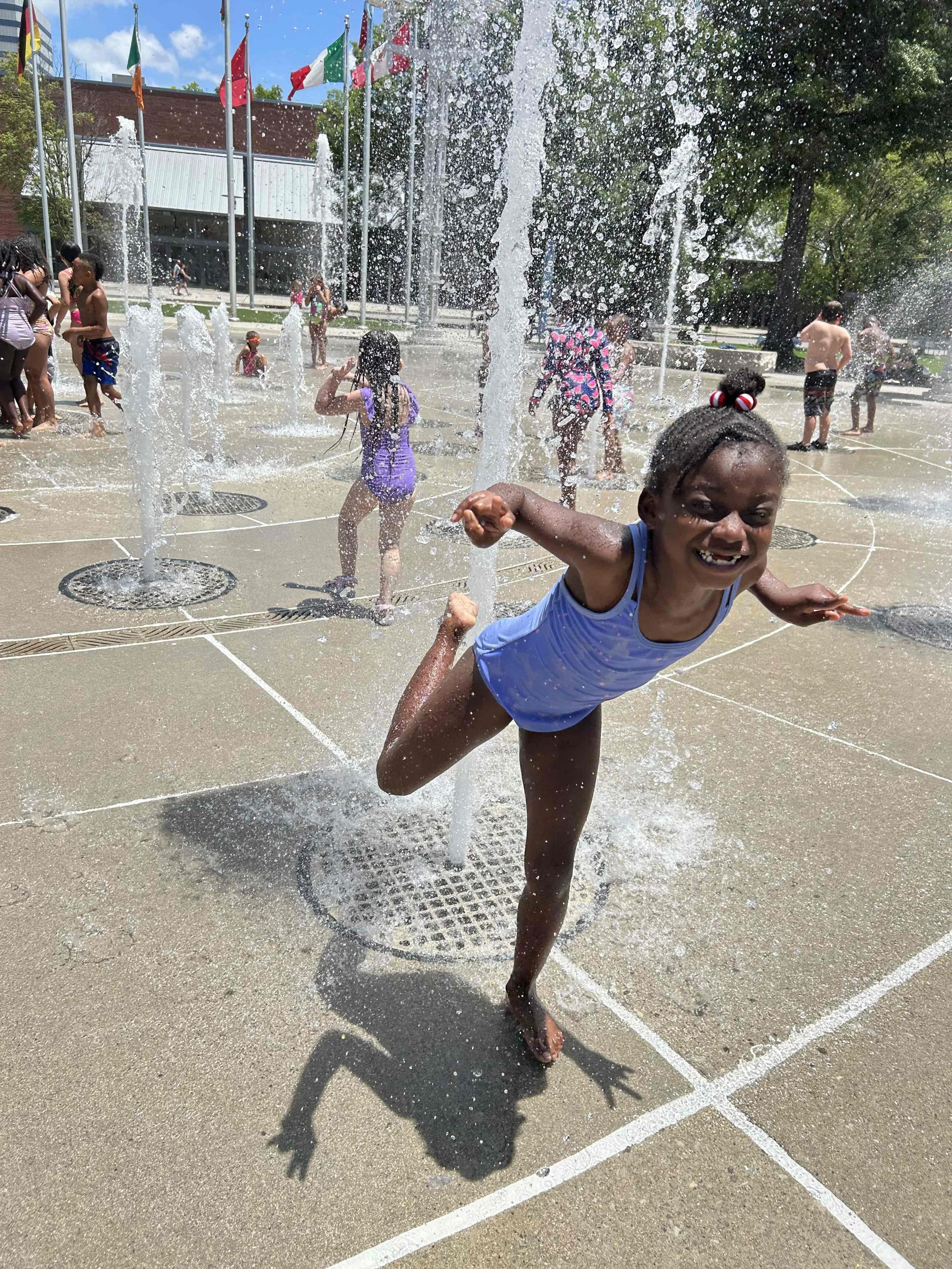 Children playing and having fun at a splash pad with water fountains on a sunny day.