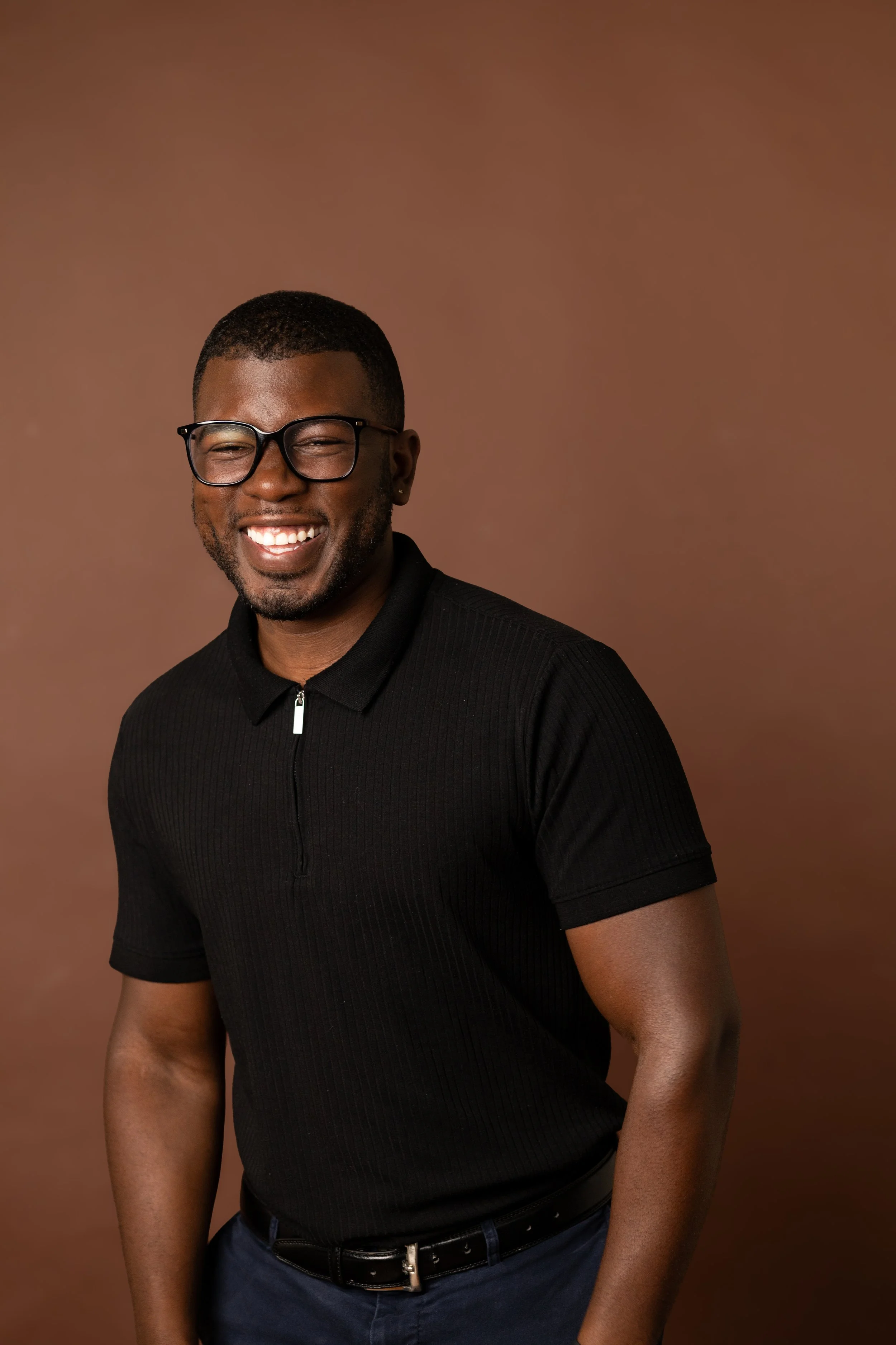 A smiling man wearing glasses smiling in black shirt