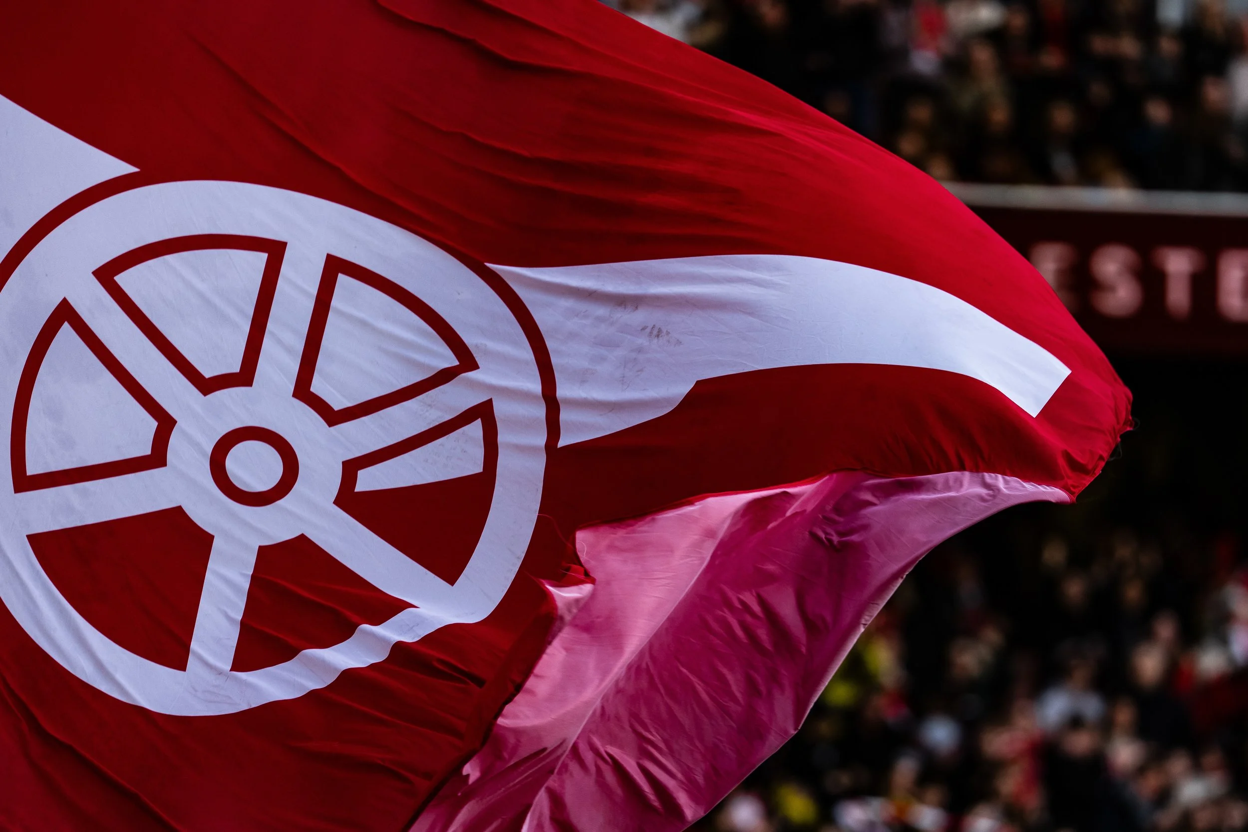 A red and white flag with a circular emblem, waving in the wind.