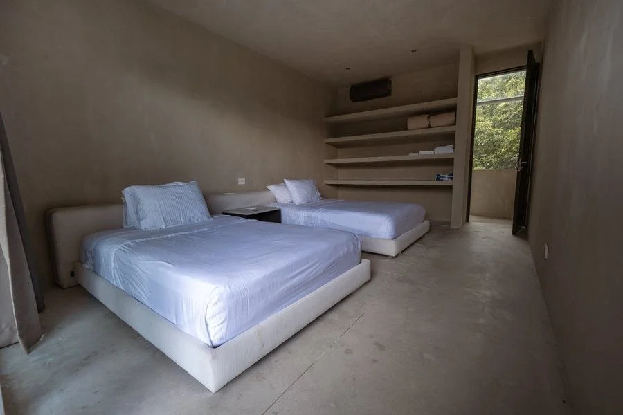 two beds freshly made in open modern concrete bedroom suite