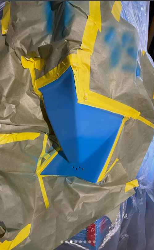 A blue Boat with yellow tape on gray paper, possibly a painted or masked surface preparing for painting.
