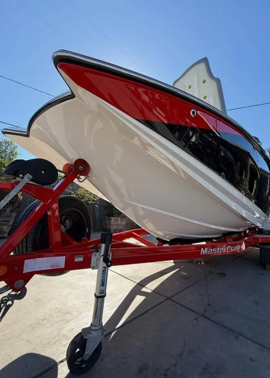 A speedboat with a white and black hull and red accents on a red trailer.