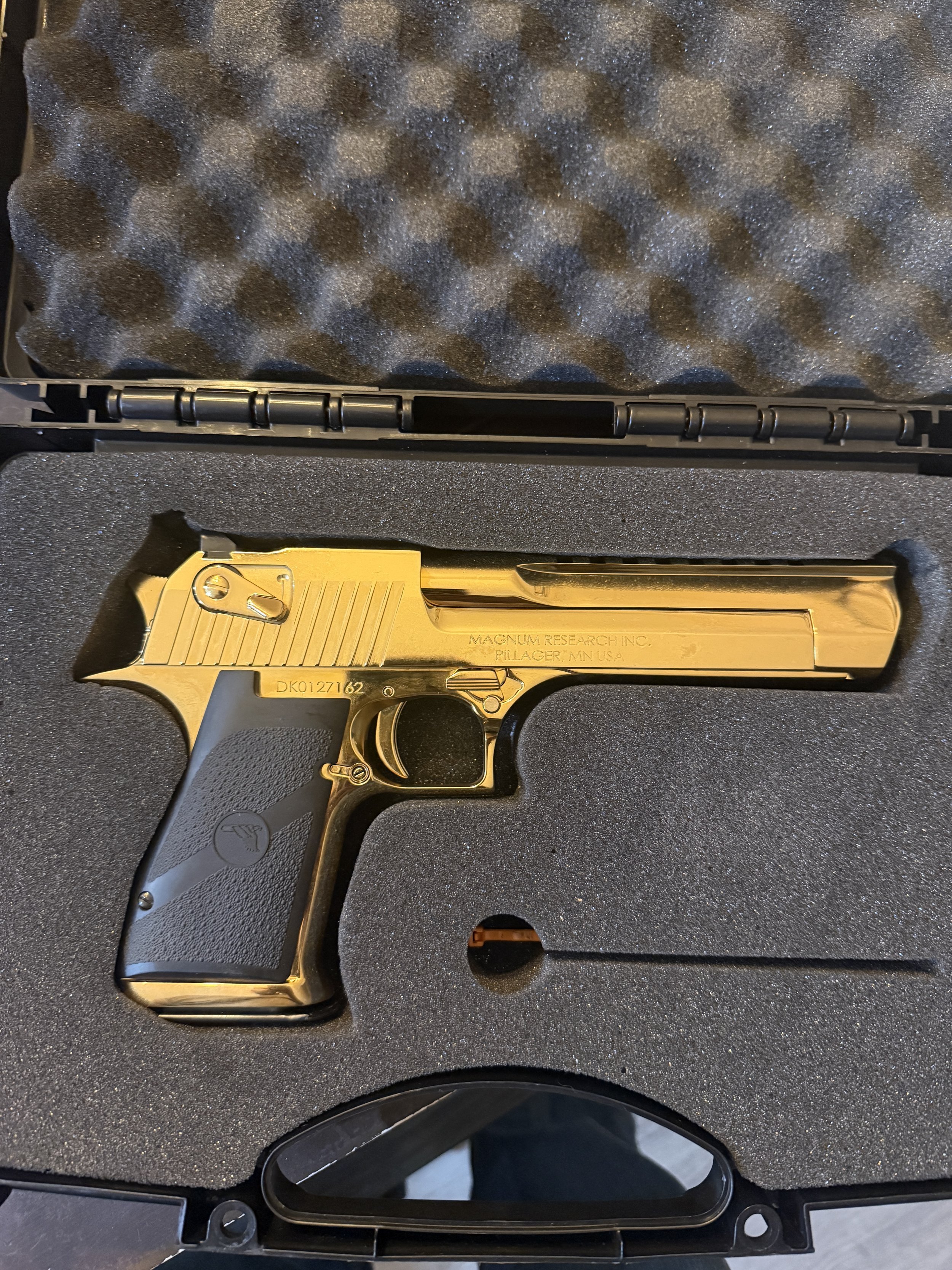 A gold-colored handgun with the words 'MAGNUM RESEARCH INC. PILAGER, MINN. USA' engraved on it, placed in a foam-lined case.