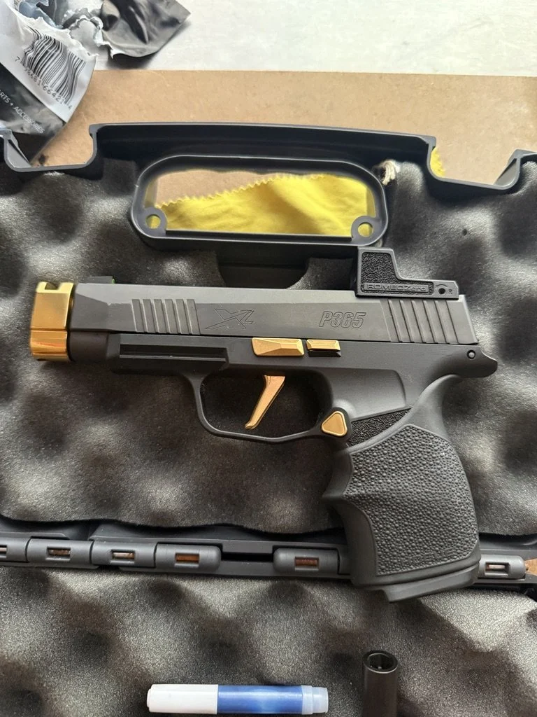 Black and gold semi-automatic handgun with textured grip, placed on foam padding inside a case.