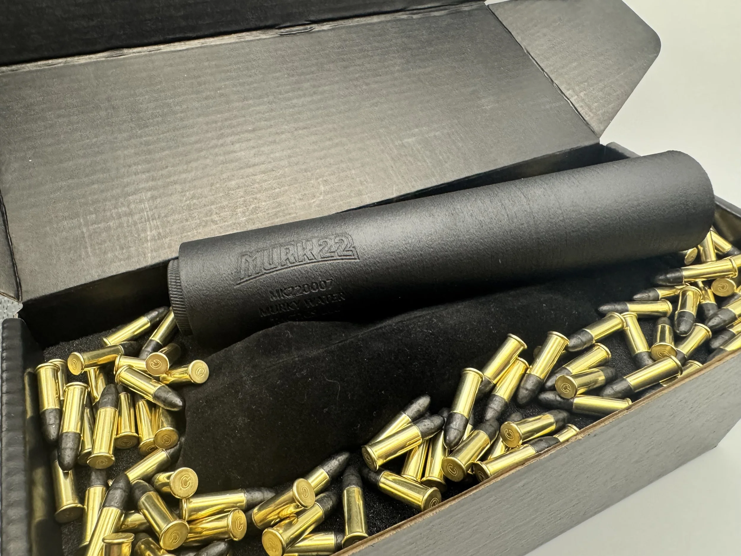 A black box filled with empty brass bullet casings and a black rubber mallet with the brand name 'LURHK22' embossed on it.