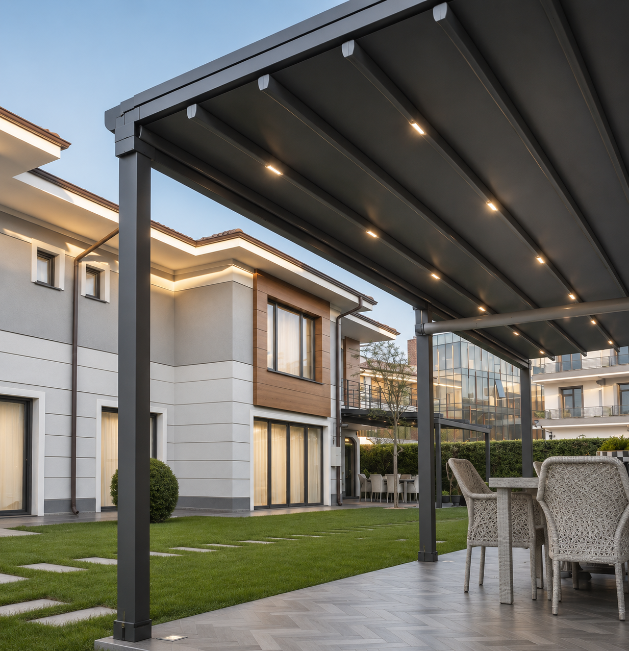 Modern residential building with outdoor patio, dining area, and a metal pergola with built-in lights.